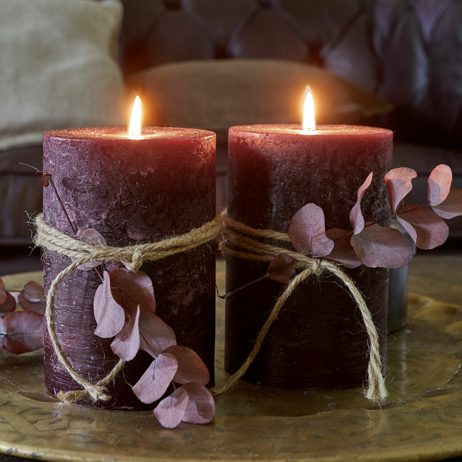 Set de 2 velas Oviedo Dos velas burdeos con cuerda natural y hojas secas sobre bandeja decorativa de latón
