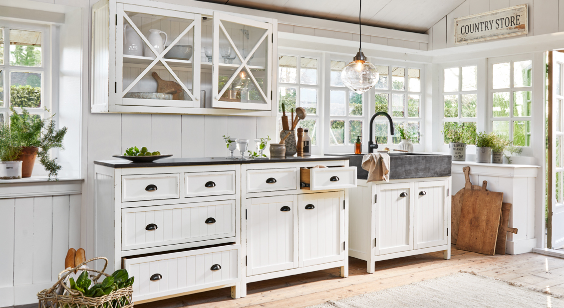 Cocina rústica blanca de madera con fregadero negro y grandes ventanas, luz natural