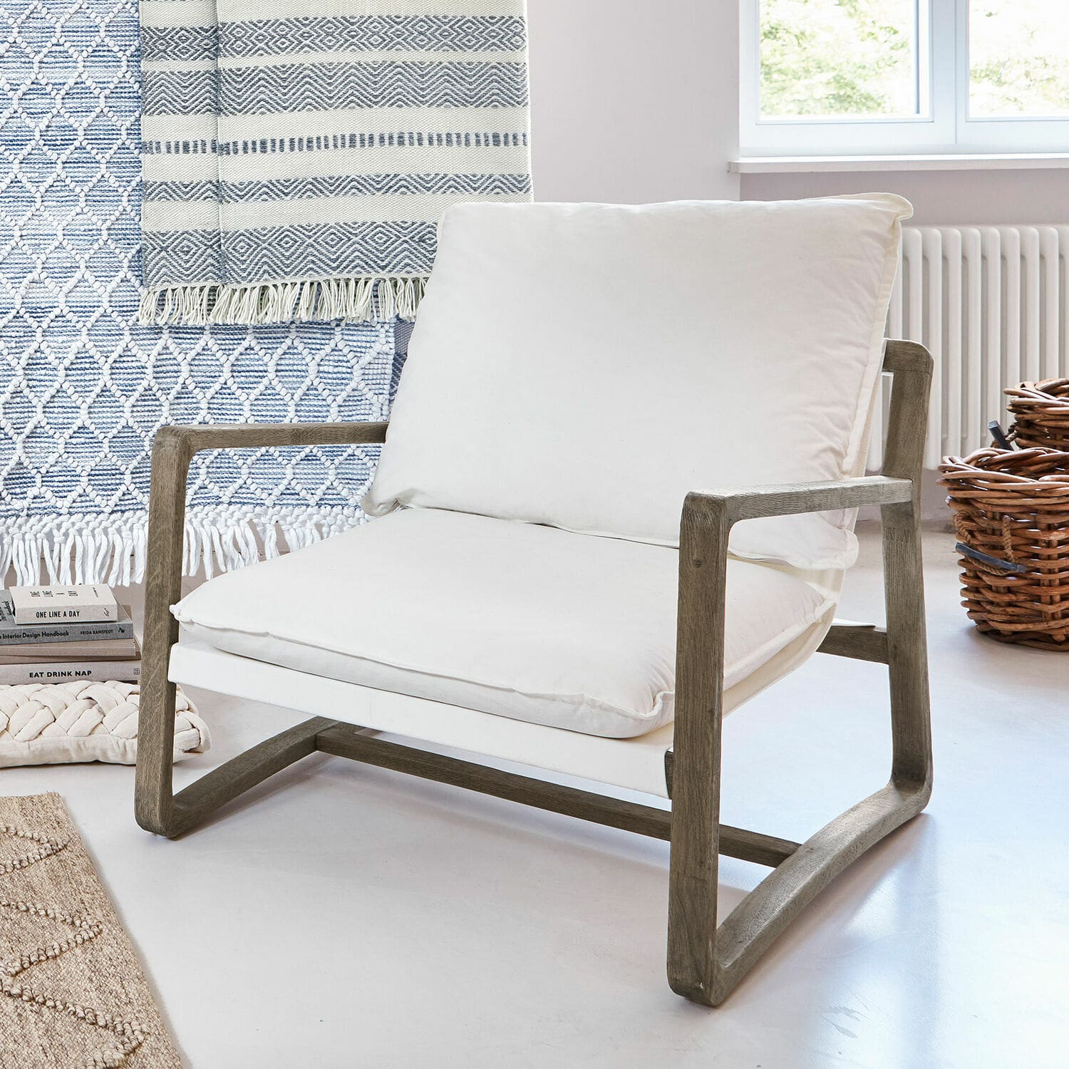 Sillón Jowna Sillón con estructura de madera y cojín blanco de algodón en interior moderno y luminoso