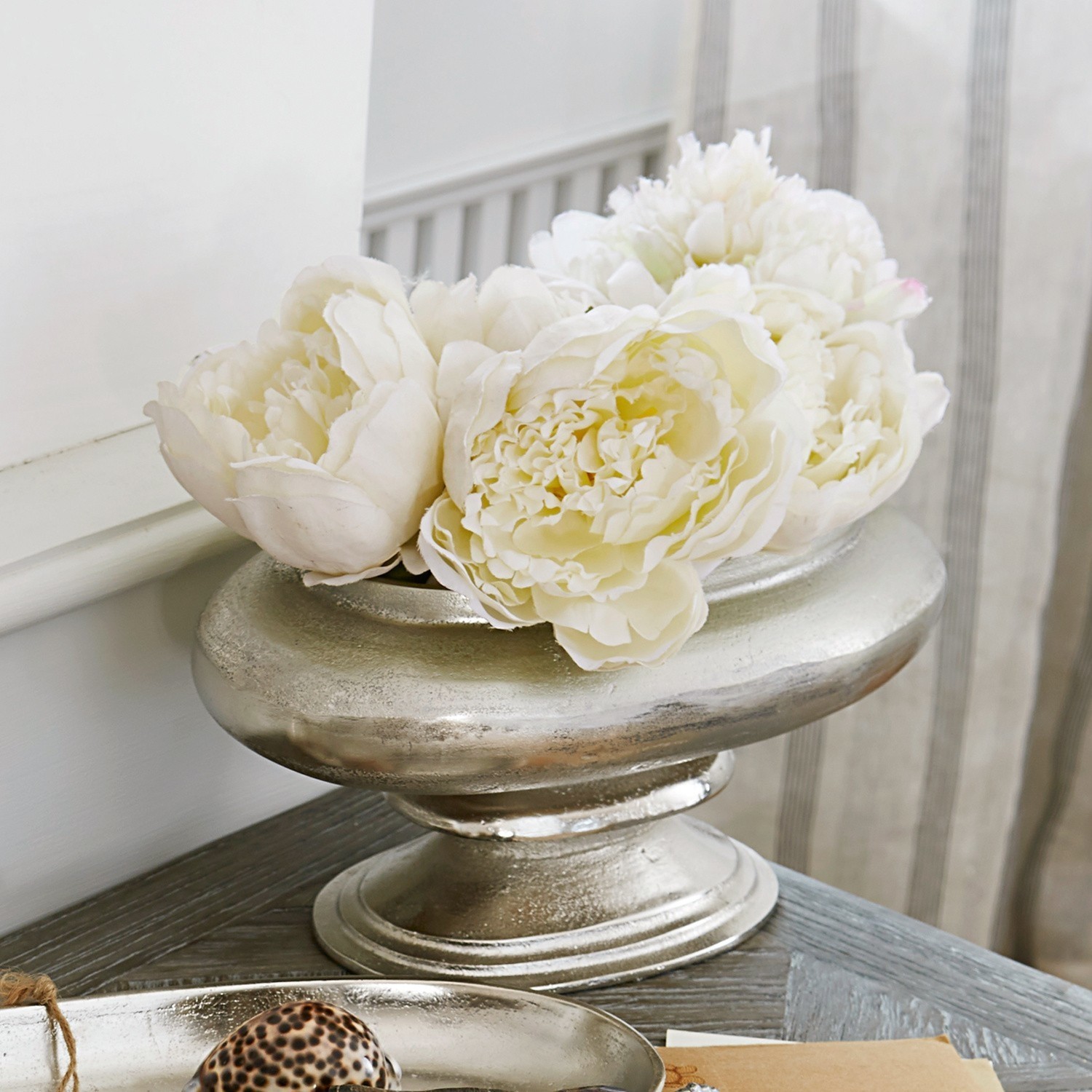 Jarrón Loyère Cuenco decorativo de metal plateado con flores blancas sobre mesa de madera en salón