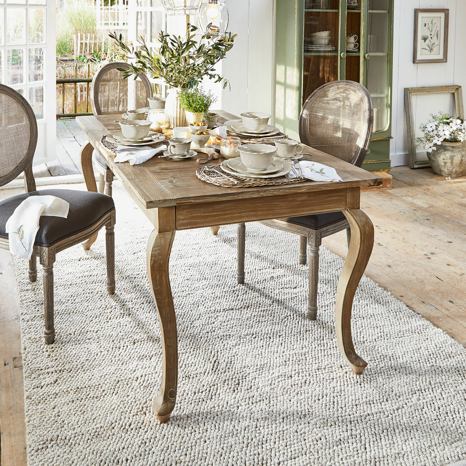 Mesa Plaish Mesa de comedor rústica de madera con patas curvas y vajilla clara en habitación luminosa