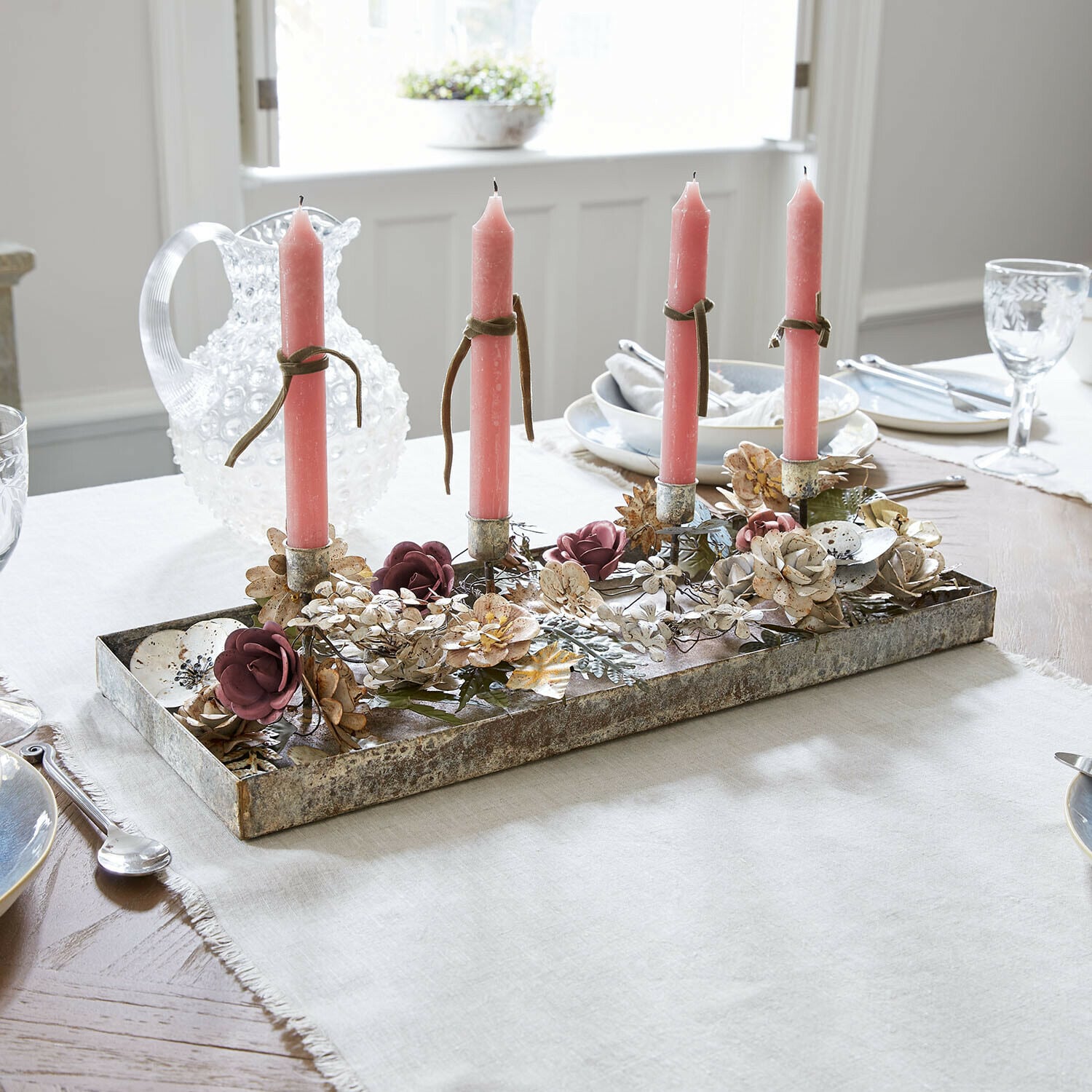 Bandeja para velas Duvérine Candelabro de metal con cuatro velas rosas y decoración floral sobre mesa de comedor