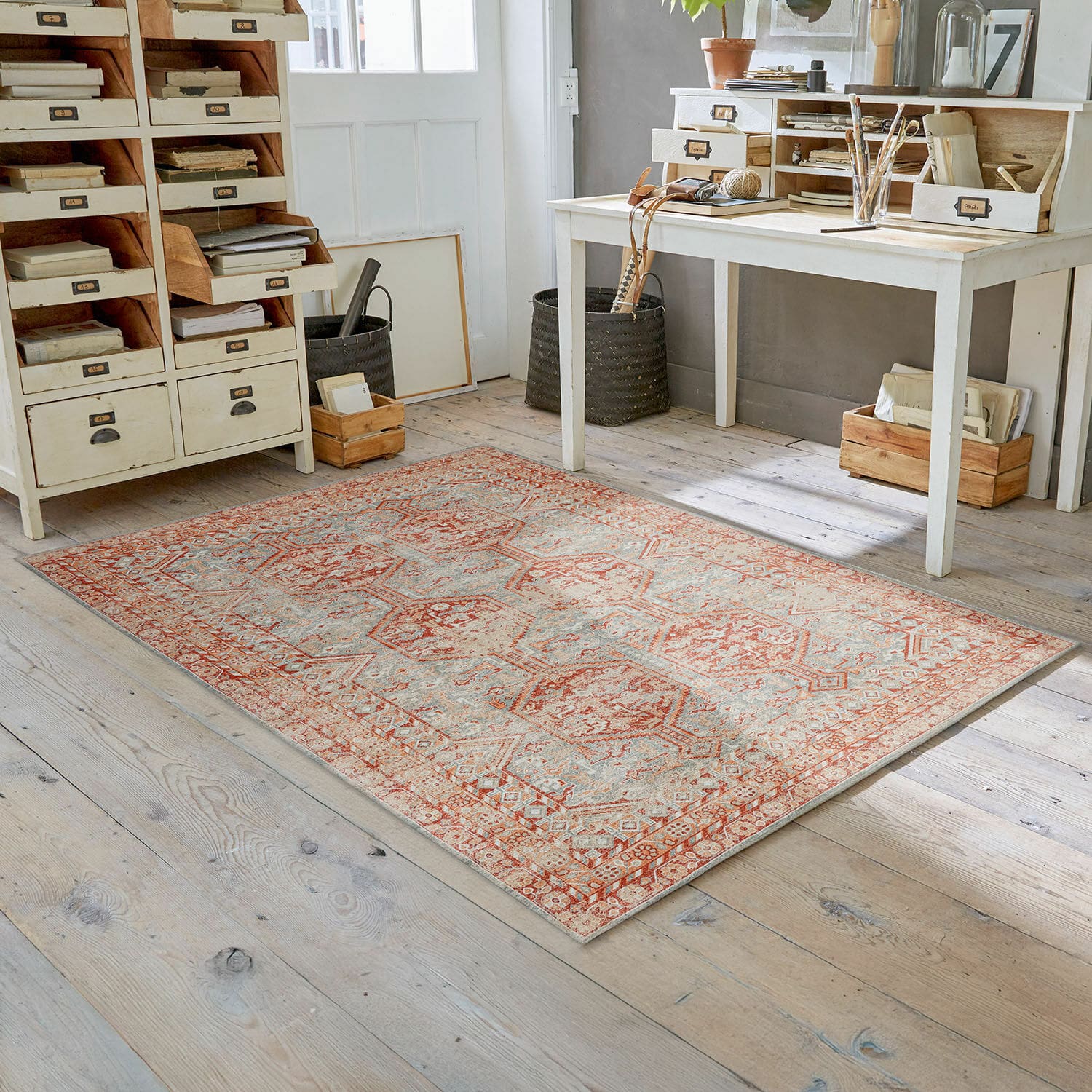 Alfombra Incantaro Alfombra con diseño en tonos rojo y beige sobre suelo de madera clara en habitación luminosa