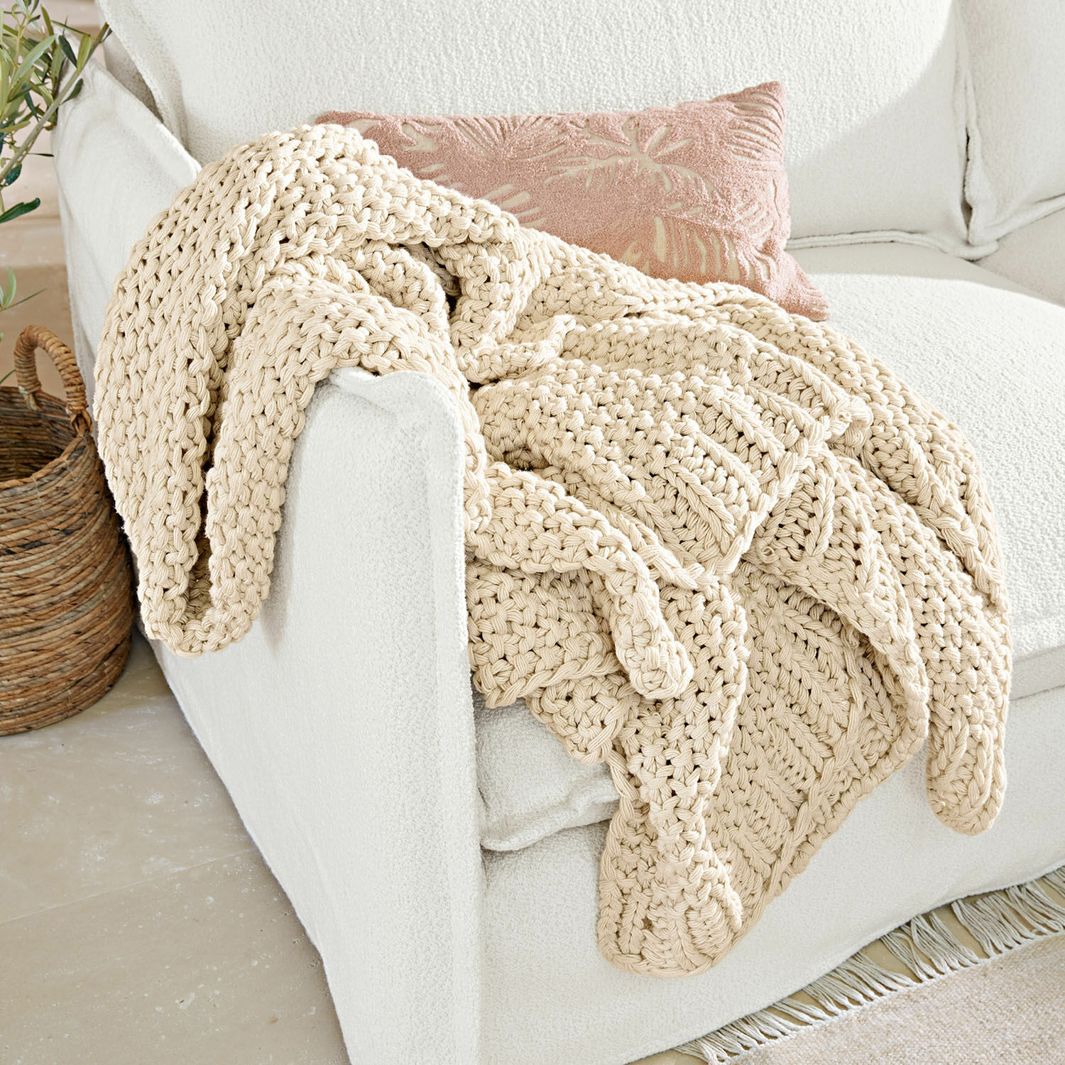 Plaid Plixoren Manta beige gruesa de algodón tejida a mano sobre sofá blanco en interior luminoso