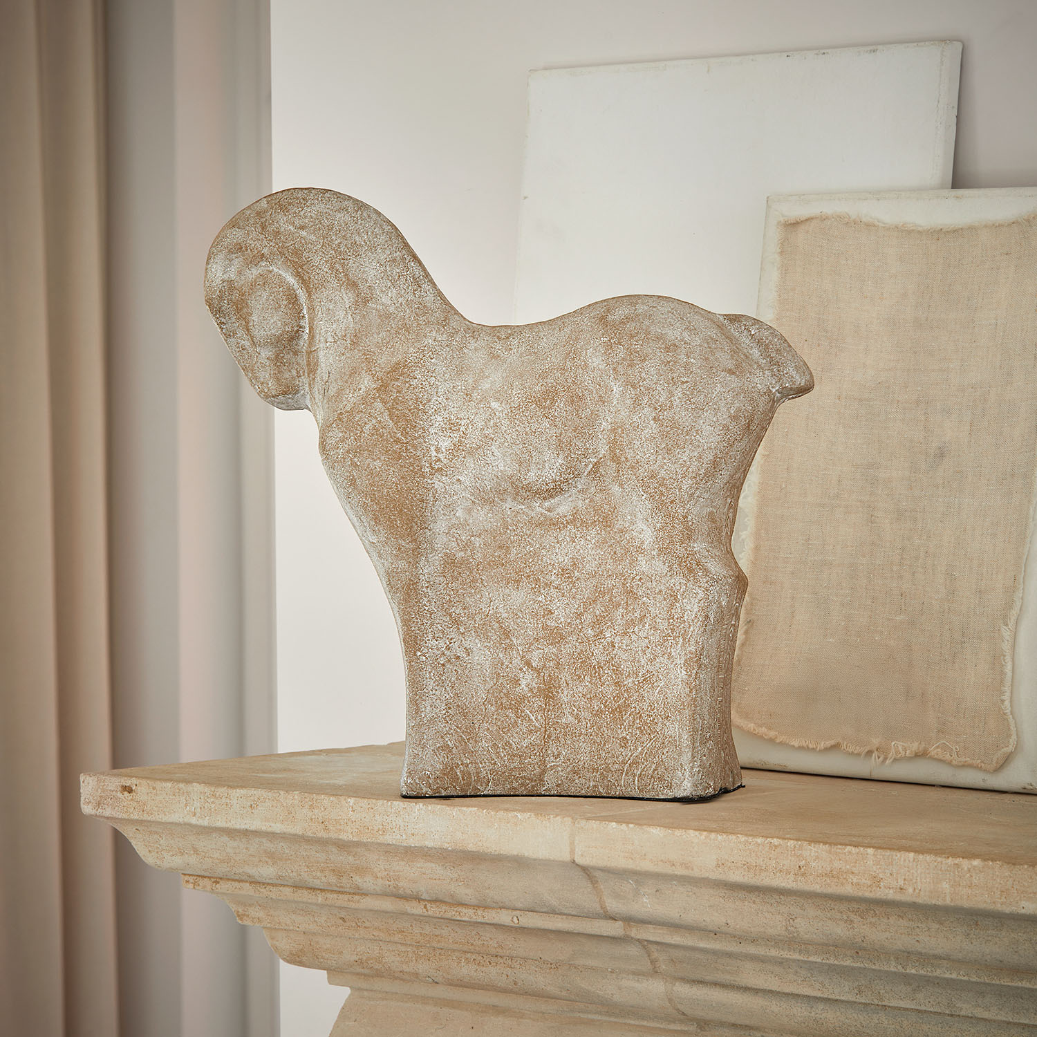 Escultura decorativa de caballo en piedra beige sobre chimenea rústica de piedra