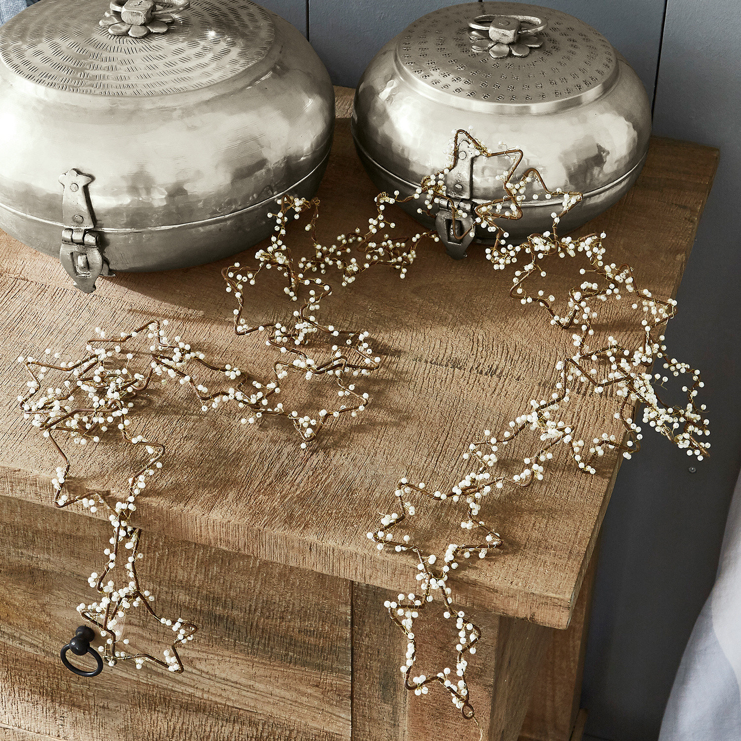 Guirnalda Ariane Guirnalda decorativa de estrellas con perlas blancas sobre mesa de madera, adorno navideño