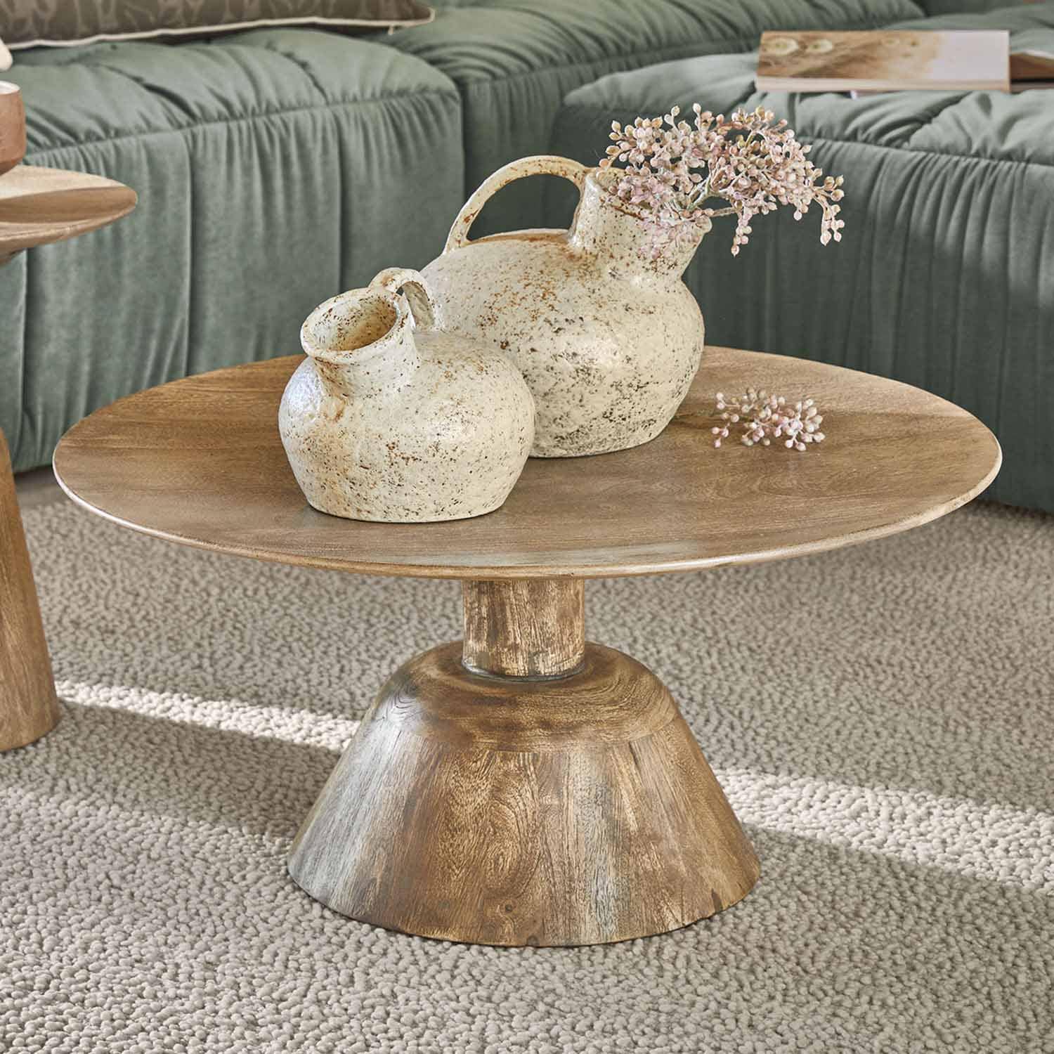 Mesa de centro de madera con dos jarrones de cerámica crema de estilo rústico sobre alfombra beige