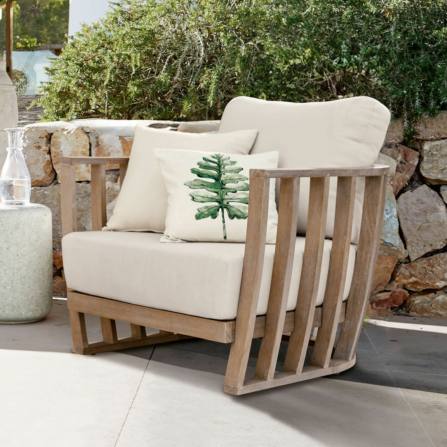 Sillón de jardín con tela beige clara y estructura de madera, cojín decorativo con diseño de hoja verde