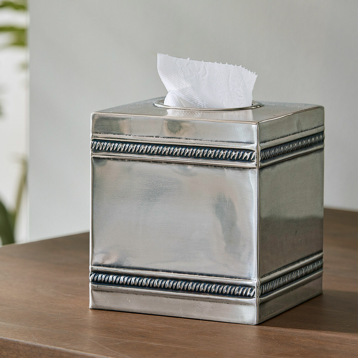 Caja de pañuelos Semoine Dispensador de pañuelos metálico plateado con diseño decorativo en los bordes sobre mesa de madera