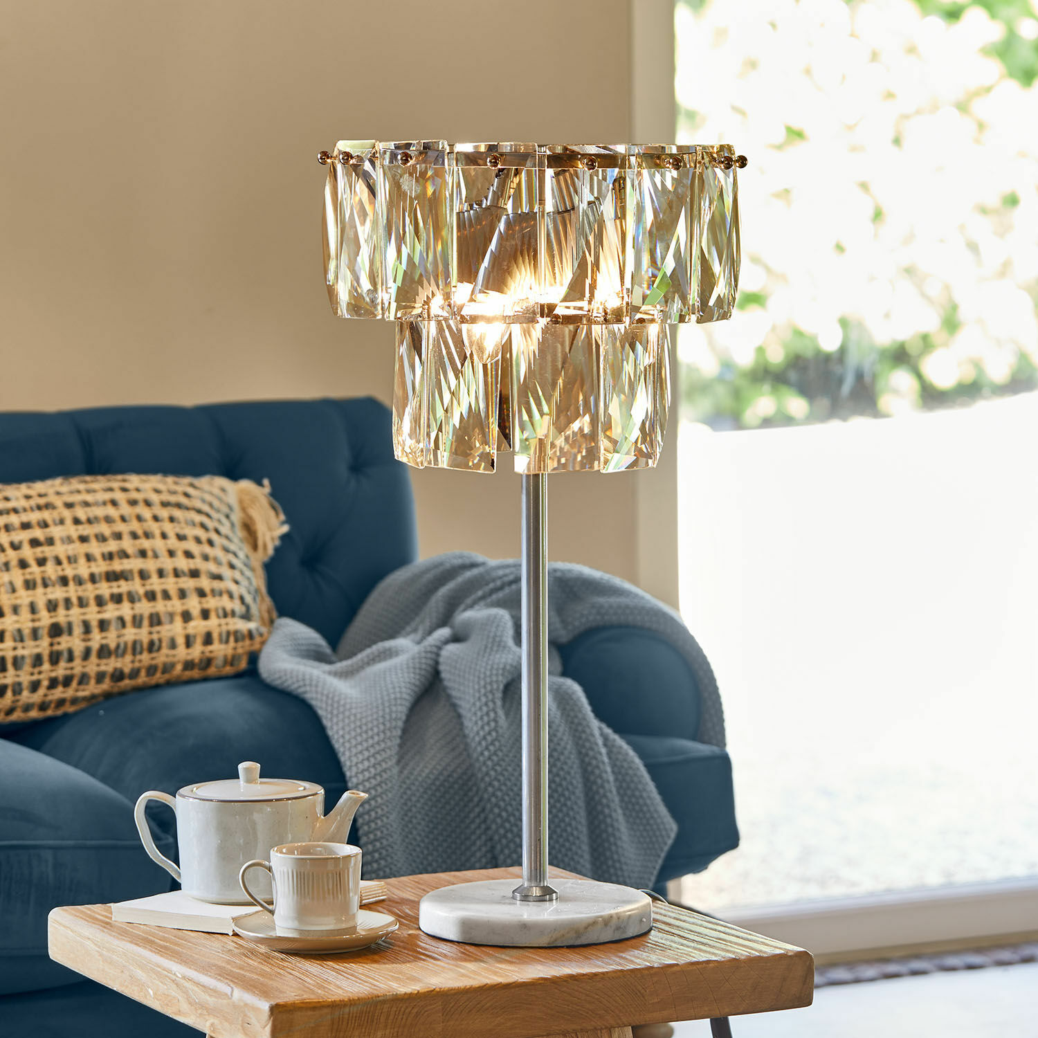 Lámpara de mesa con elementos de cristal y base de mármol en sala moderna