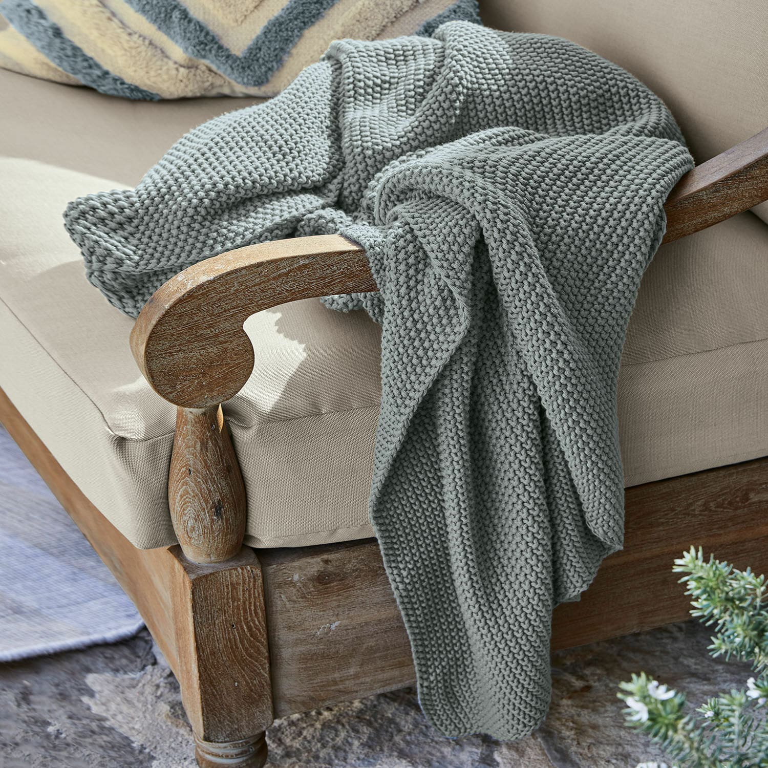 Plaid Ancy Manta gris gruesa de punto suave sobre sillón de madera con cojín beige