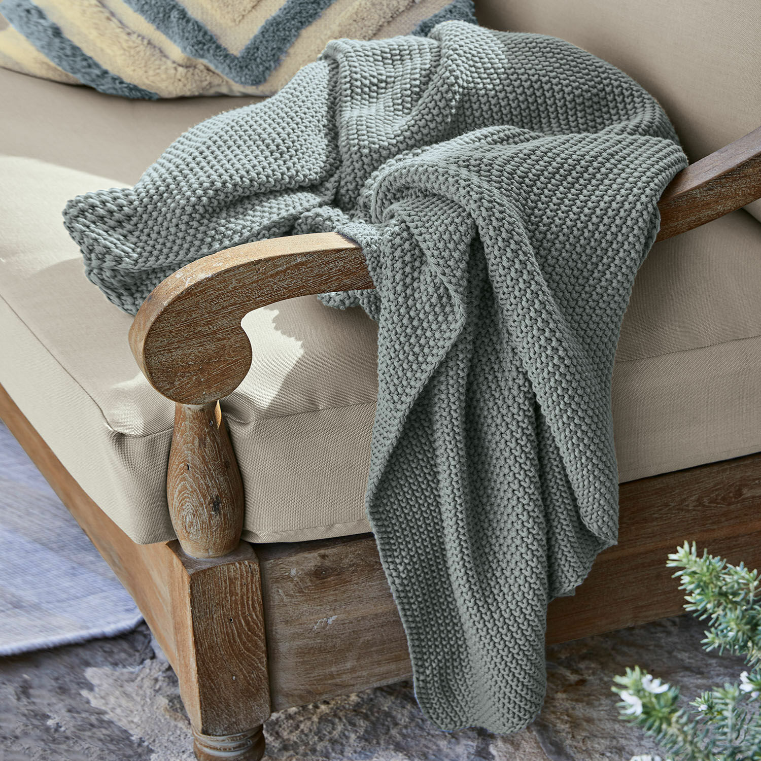 Plaid Ancy Manta gris gruesa de punto suave sobre sillón de madera con cojín beige