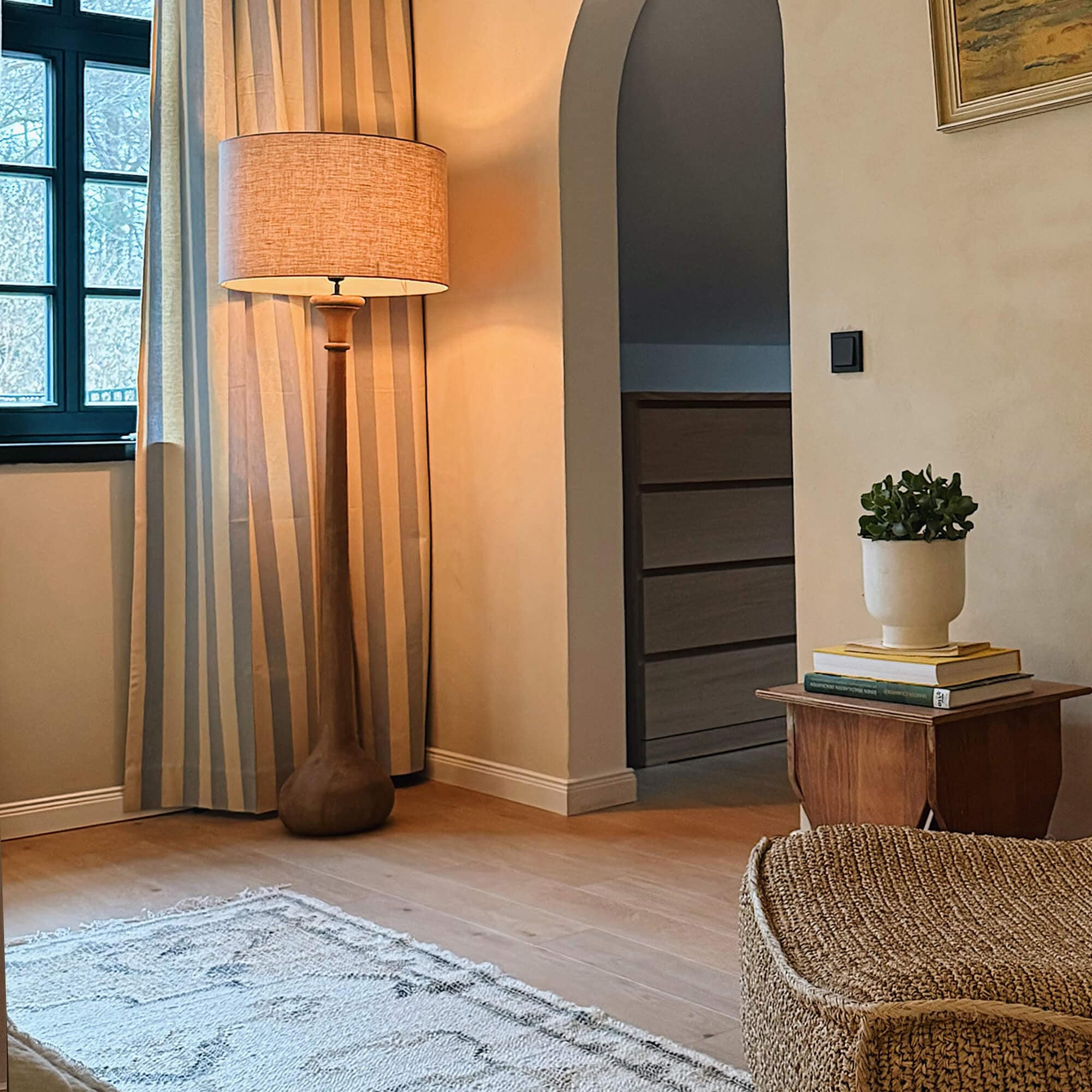 Lámpara de pie con base de madera y pantalla beige en sala acogedora con alfombra clara