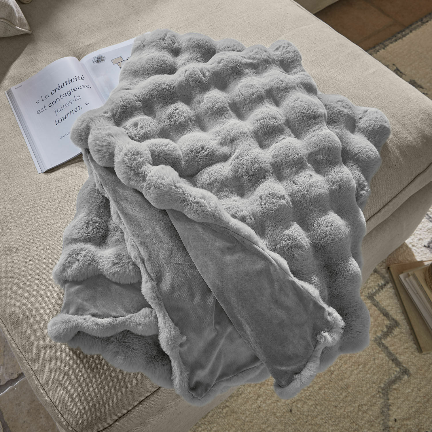 Plaid Zalina Manta gris suave con diseño de piel sobre sofá beige, ideal para decoración y calidez interior