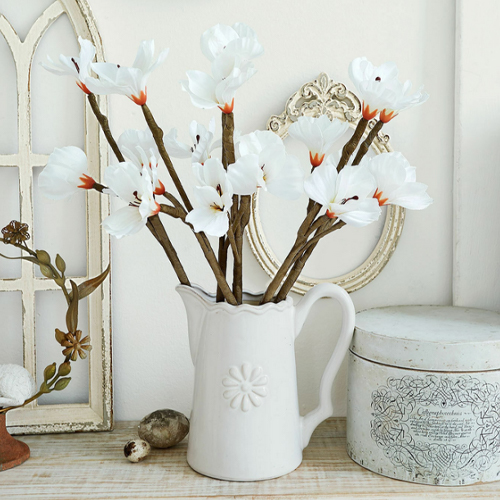 Jarra de cerámica blanca con flores decorativas sobre mesa de madera, estilo vintage, decoración interior
