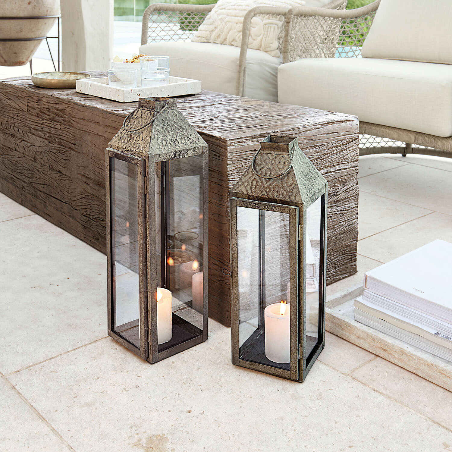 Dos faroles de metal con velas blancas sobre suelo claro en sala de estar moderna