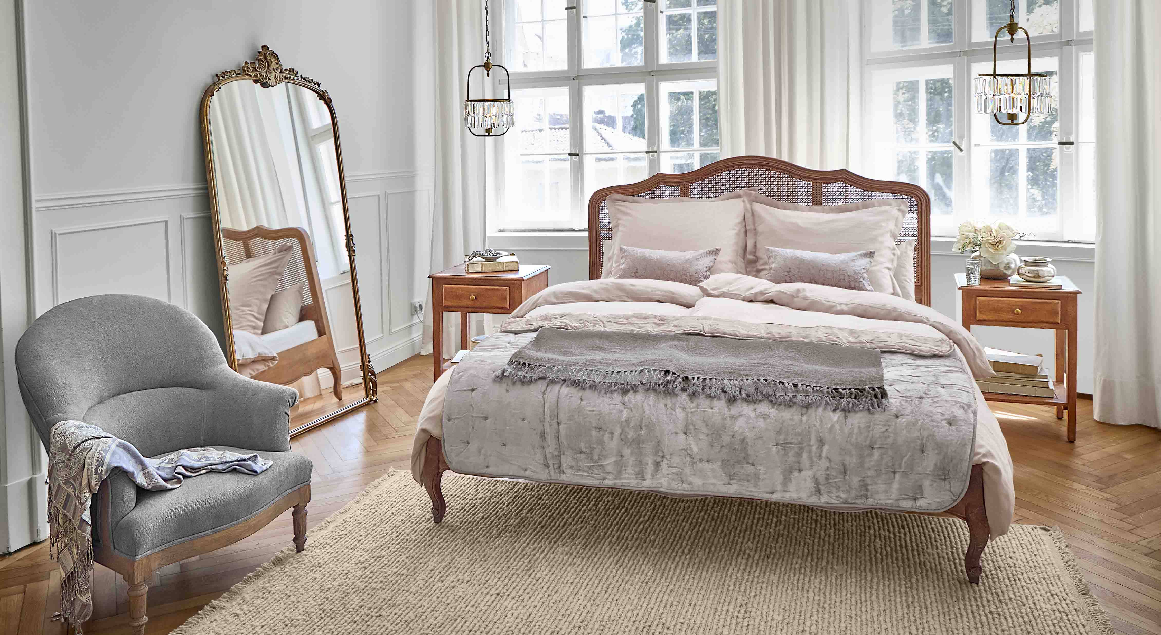 Dormitorio acogedor con cama de madera y sillón gris sobre alfombra de fibras naturales