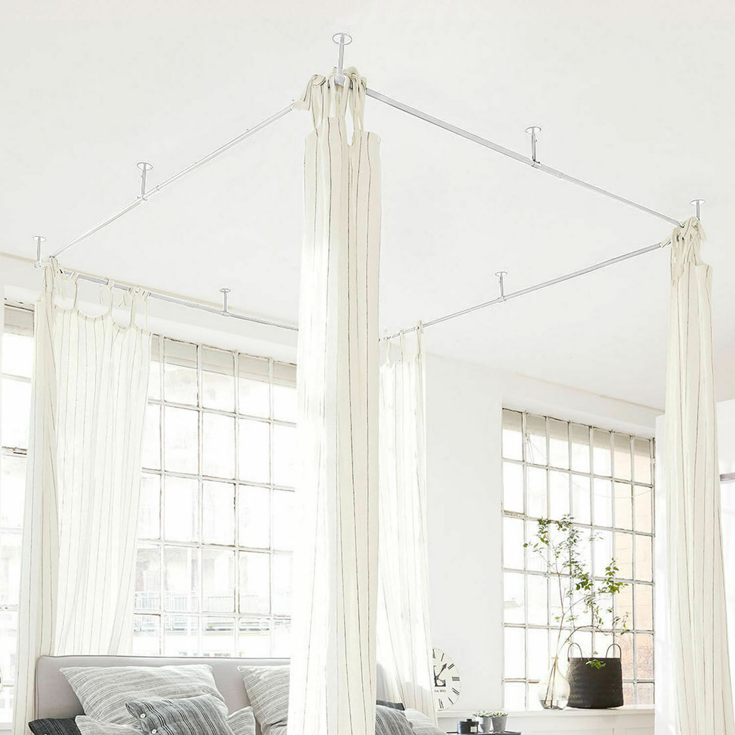 Cortinas blancas con finas rayas colgadas de estructura metálica en techo en interior luminoso