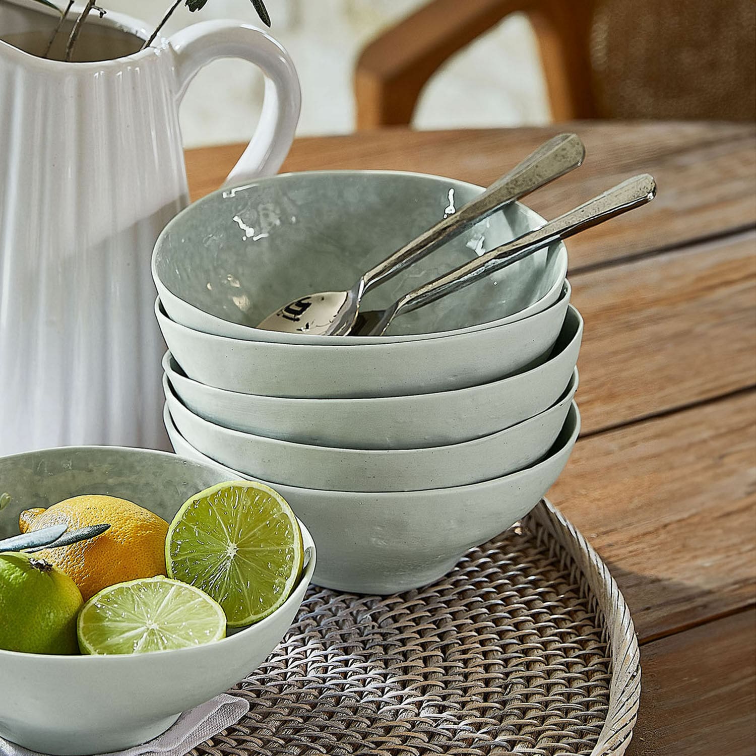 Set de 6 cuencos Braganza Juego de cuencos de cerámica gris sobre bandeja de mimbre con frutas y cucharas