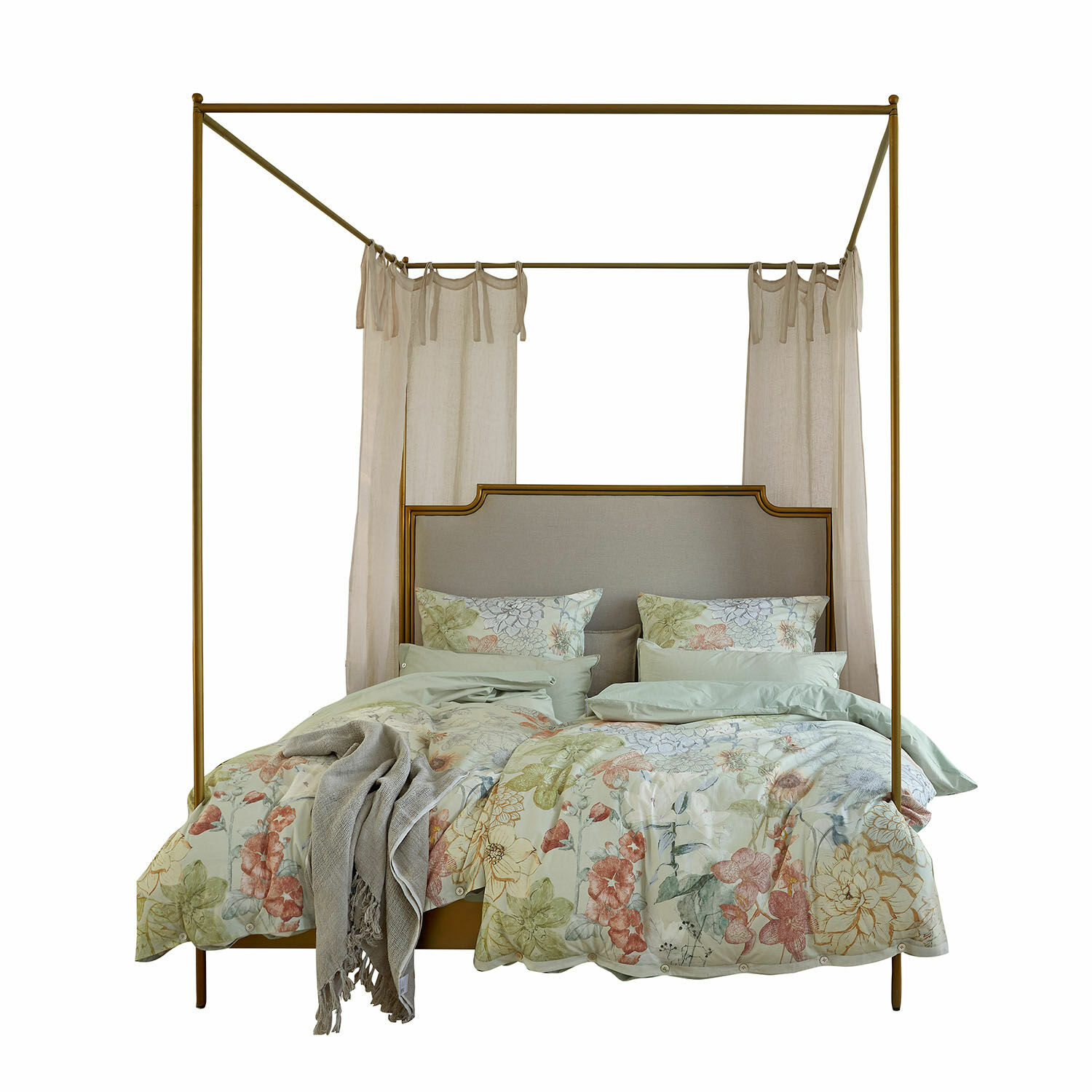 Cama con dosel de metal color latón y ropa de cama floral en tonos pastel para dormitorio elegante