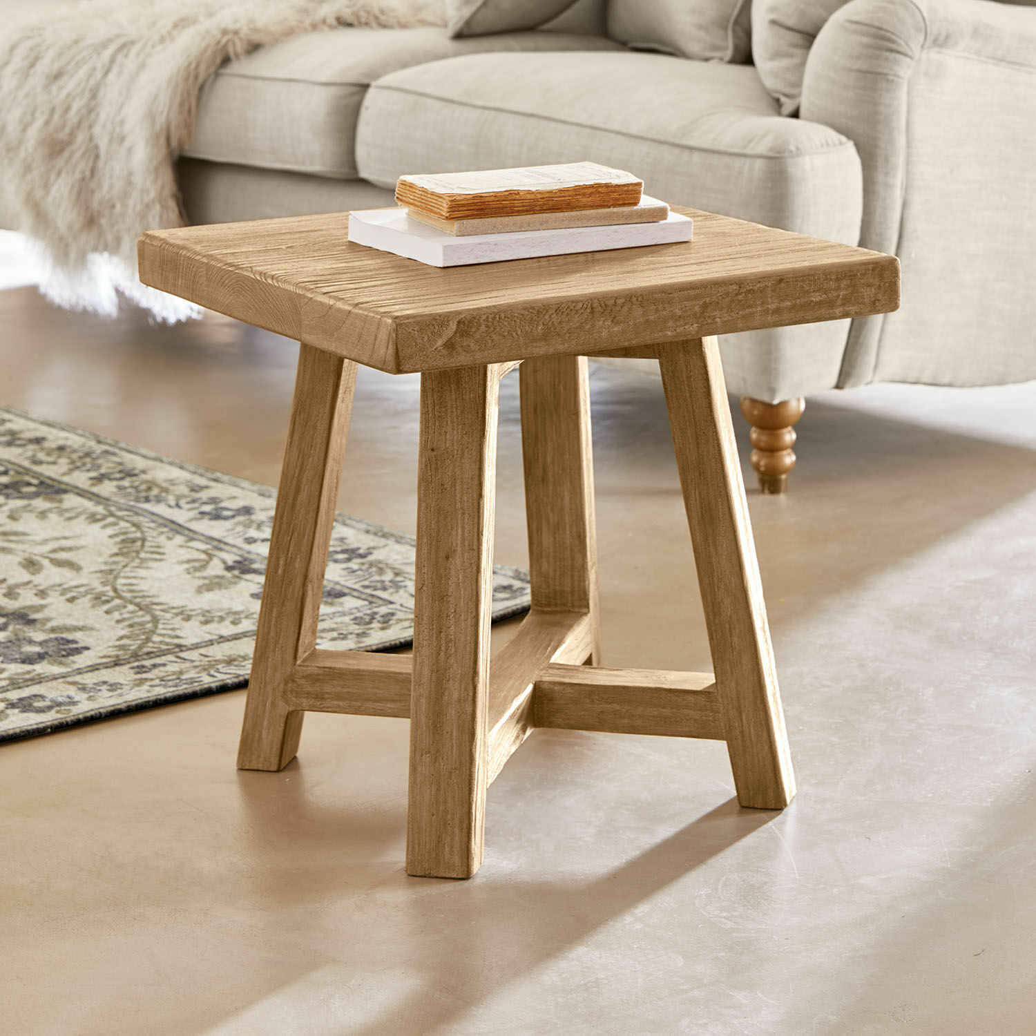Mesa auxiliar Eldonbury Mesa de centro cuadrada de madera natural frente a un sofá beige y alfombra decorativa