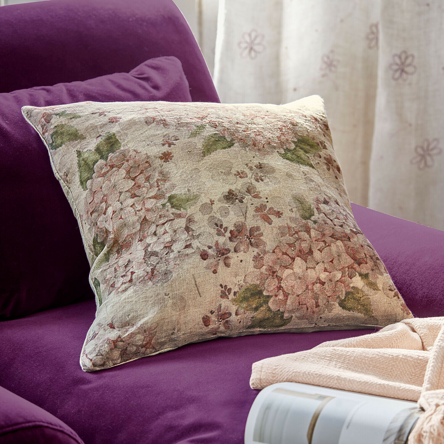 Cojín decorativo de lino con diseño floral sobre sofá morado, accesorio acogedor para el hogar
