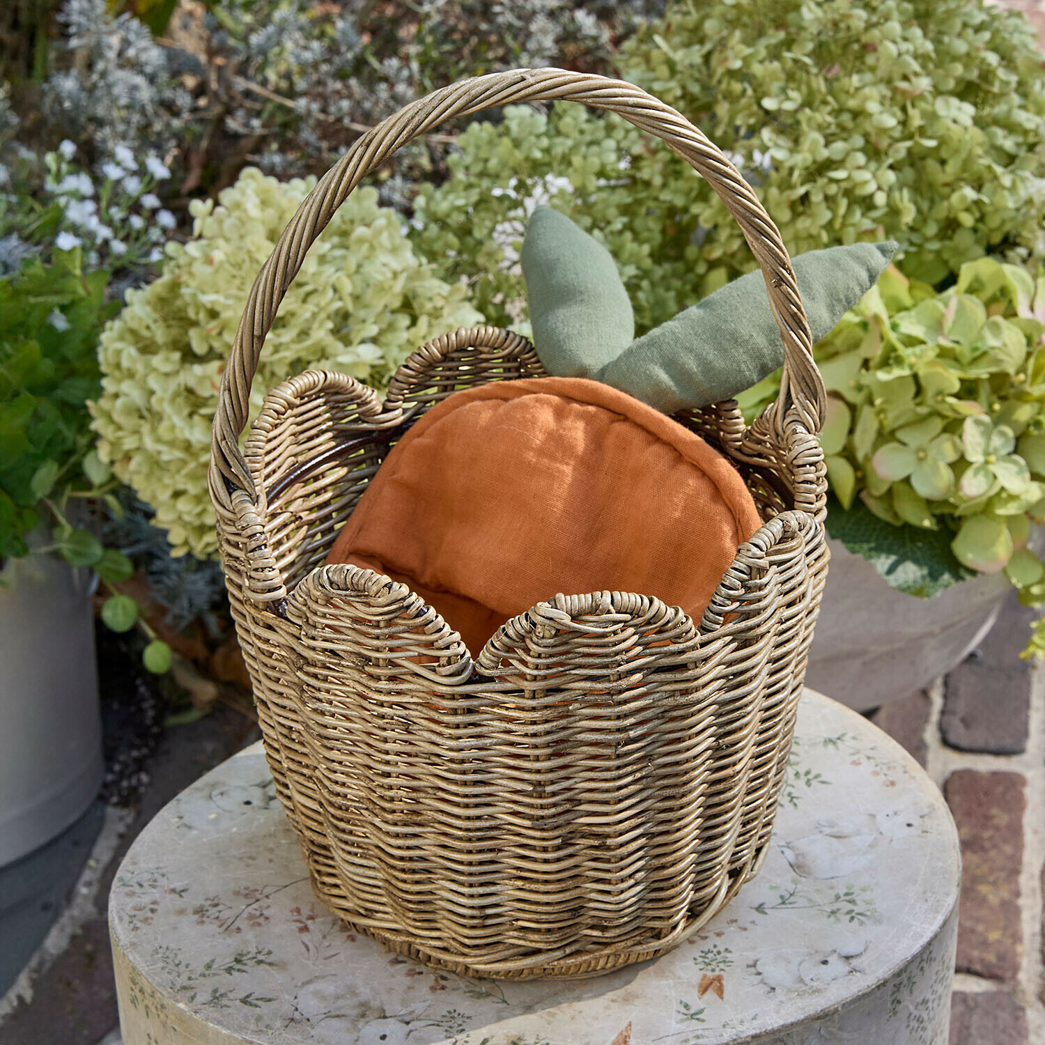 Cesta Whimsywood Cesta de mimbre con cojín naranja y hojas verdes, decoración de jardín sobre mesa redonda