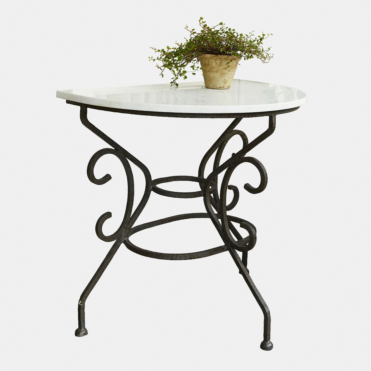 Mesa redonda con tapa de mármol blanco y base de metal forjado negro, planta decorativa encima