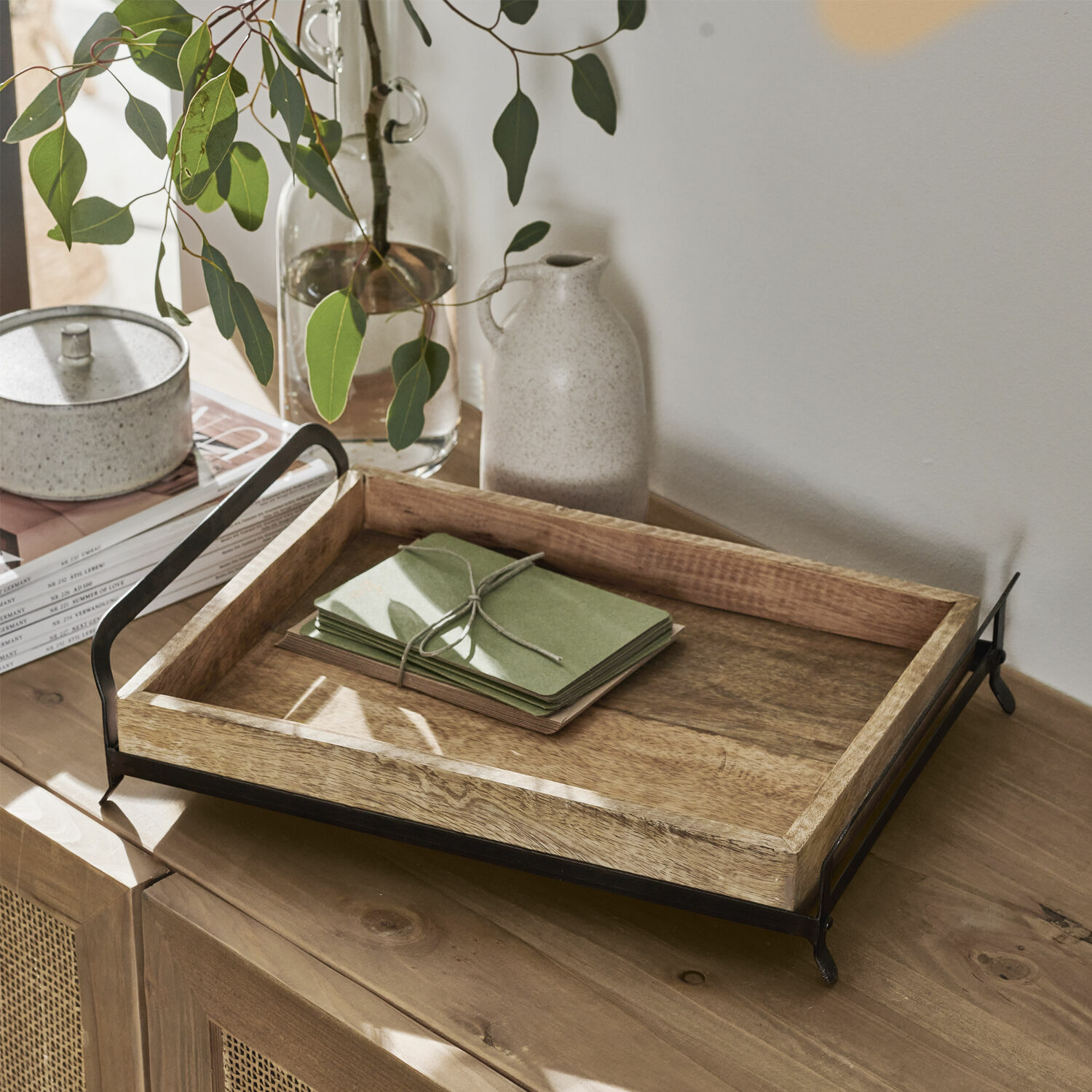 Bandeja Troyes Bandeja de madera con asas de metal negro sobre mueble de madera con decoración natural