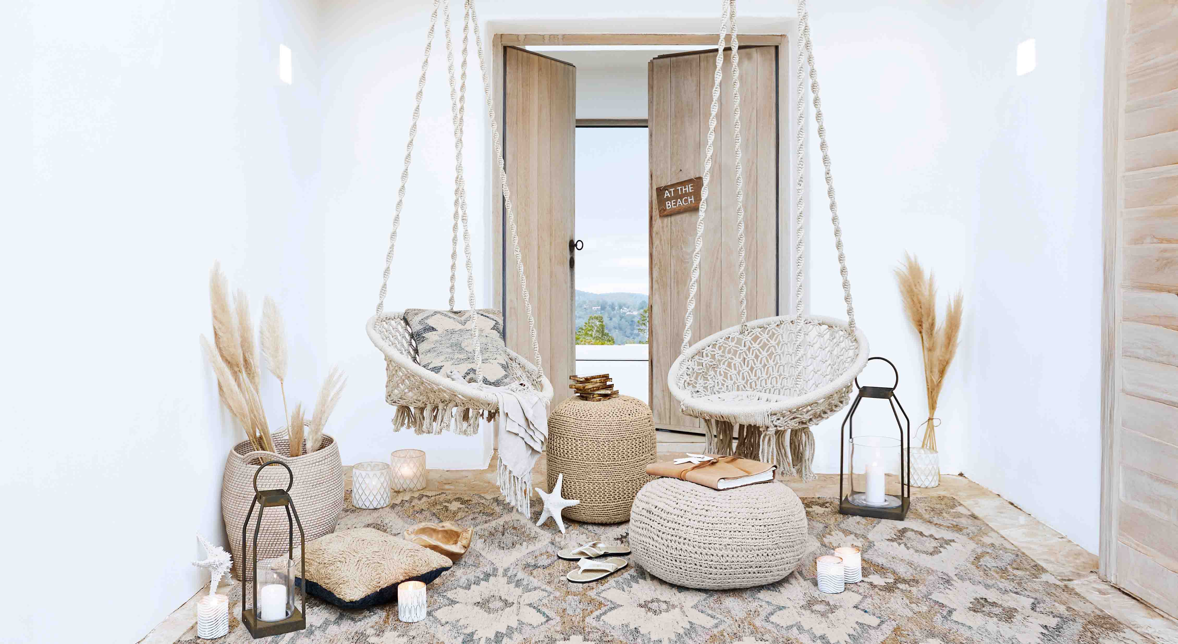 Salón acogedor con sillas colgantes blancas de macramé y decoración natural estilo bohemio