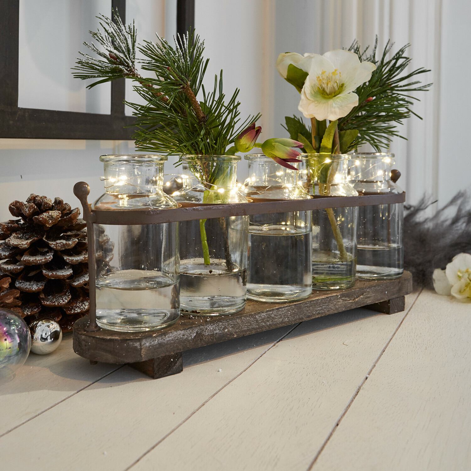 Conjunto decorativo de jarrones de vidrio sobre base de madera con ramas verdes y luces LED