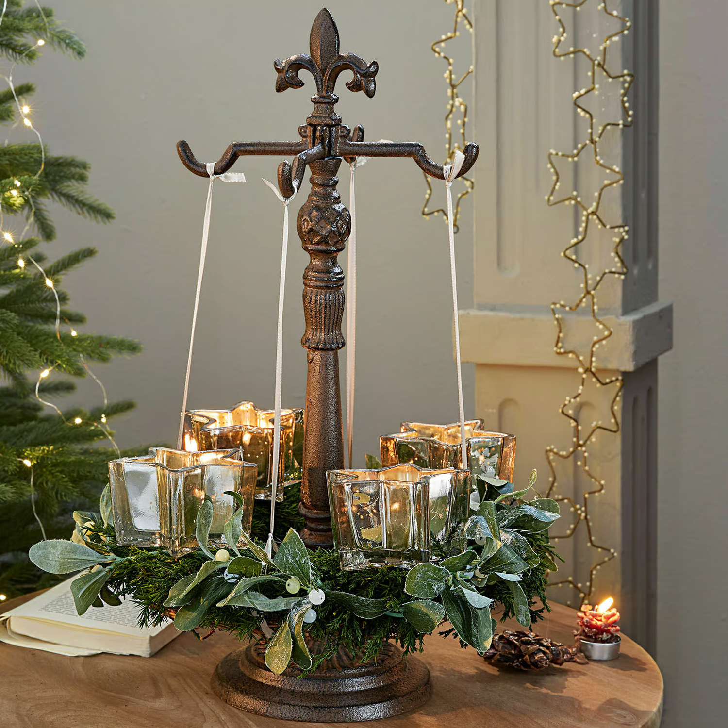 Soporte metálico con cuatro portavelas de vidrio en forma de estrella colgantes y corona verde decorativa