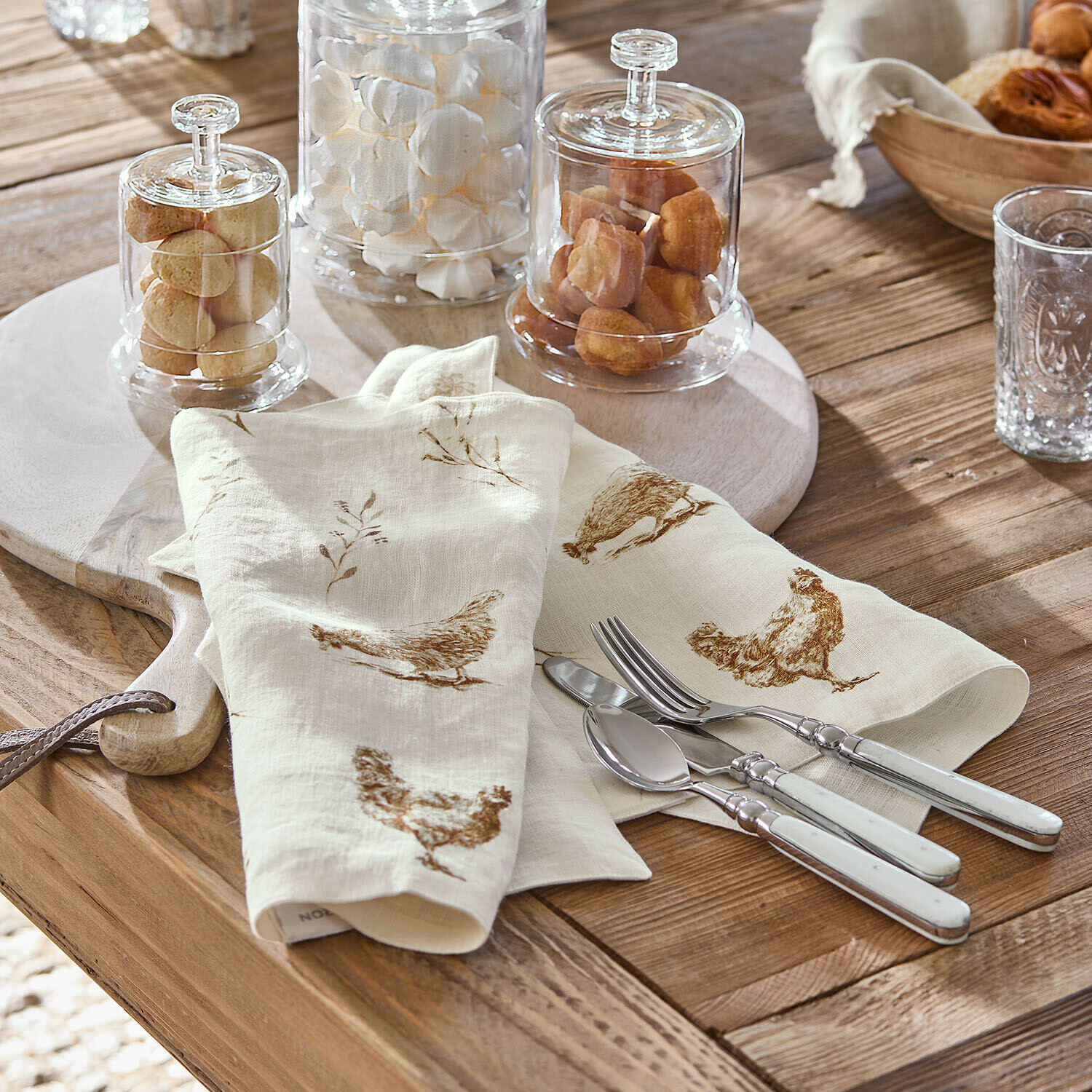 Set de 2 manteles individuales Chavéreau Servilletas de lino crema con estampado marrón de gallinas sobre mesa de madera con cubiertos