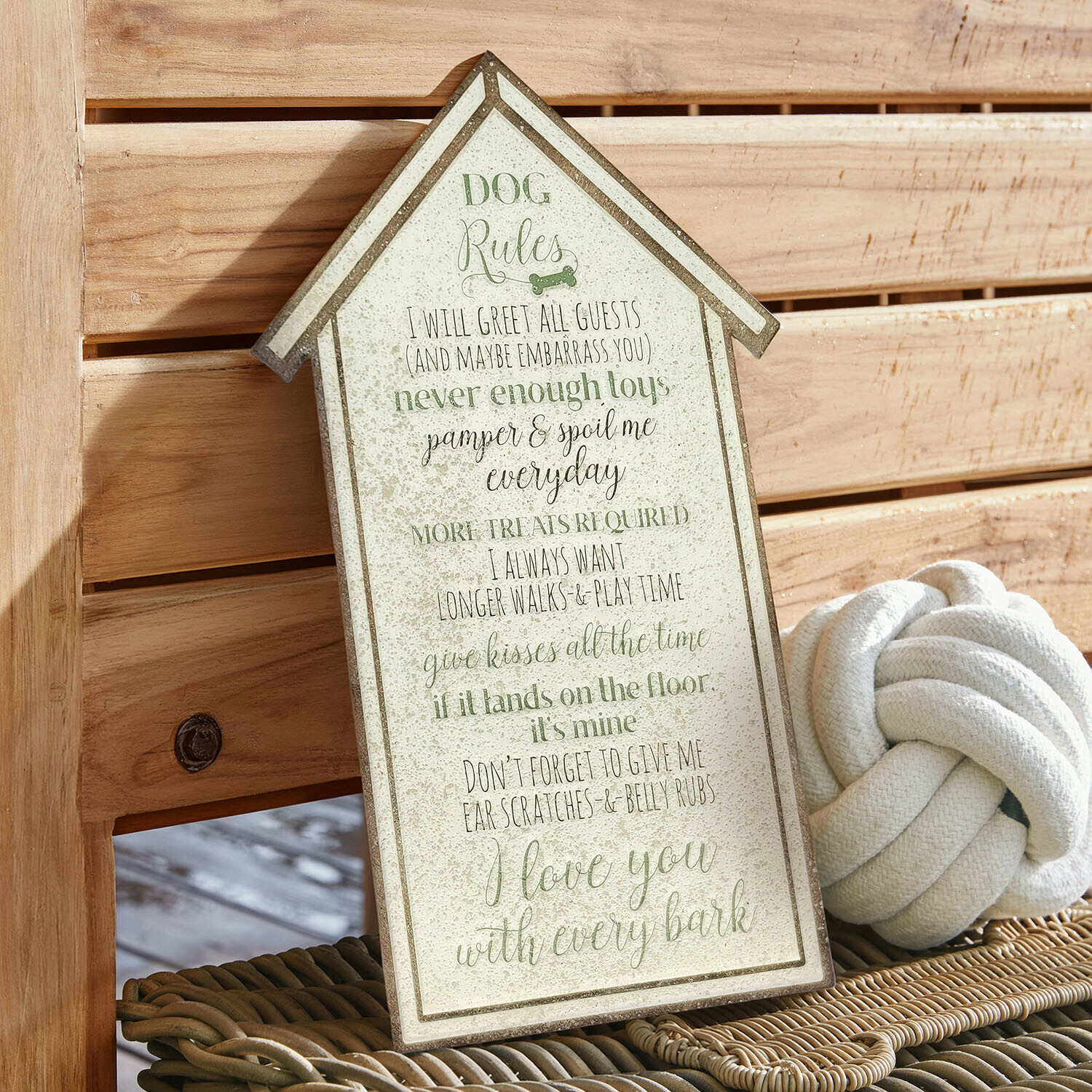 Cartel decorativo en forma de casa con reglas para perros en colores verde y beige sobre fondo de madera