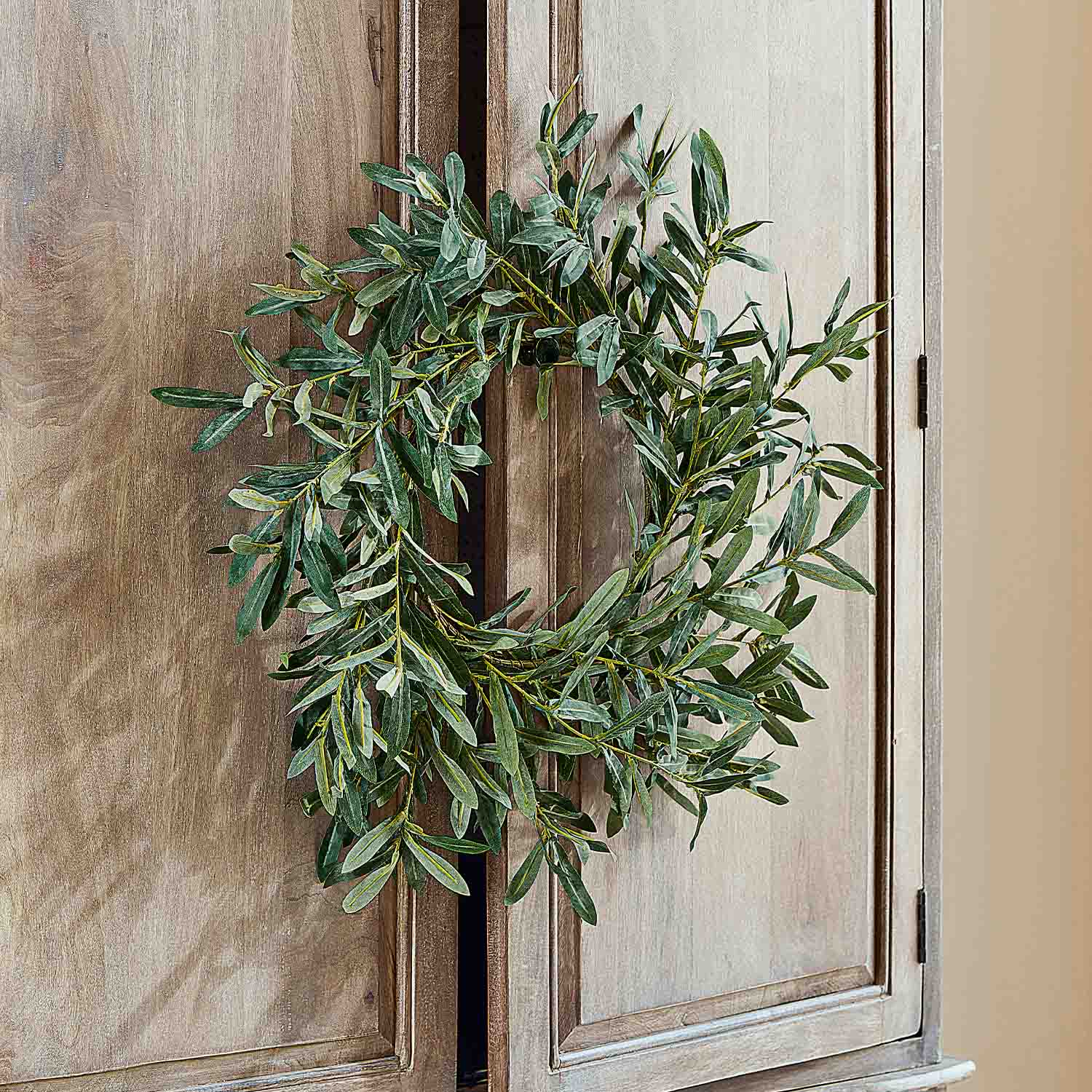 Corona decorativa de hojas verdes colgada en puerta de madera, decoración natural para interiores