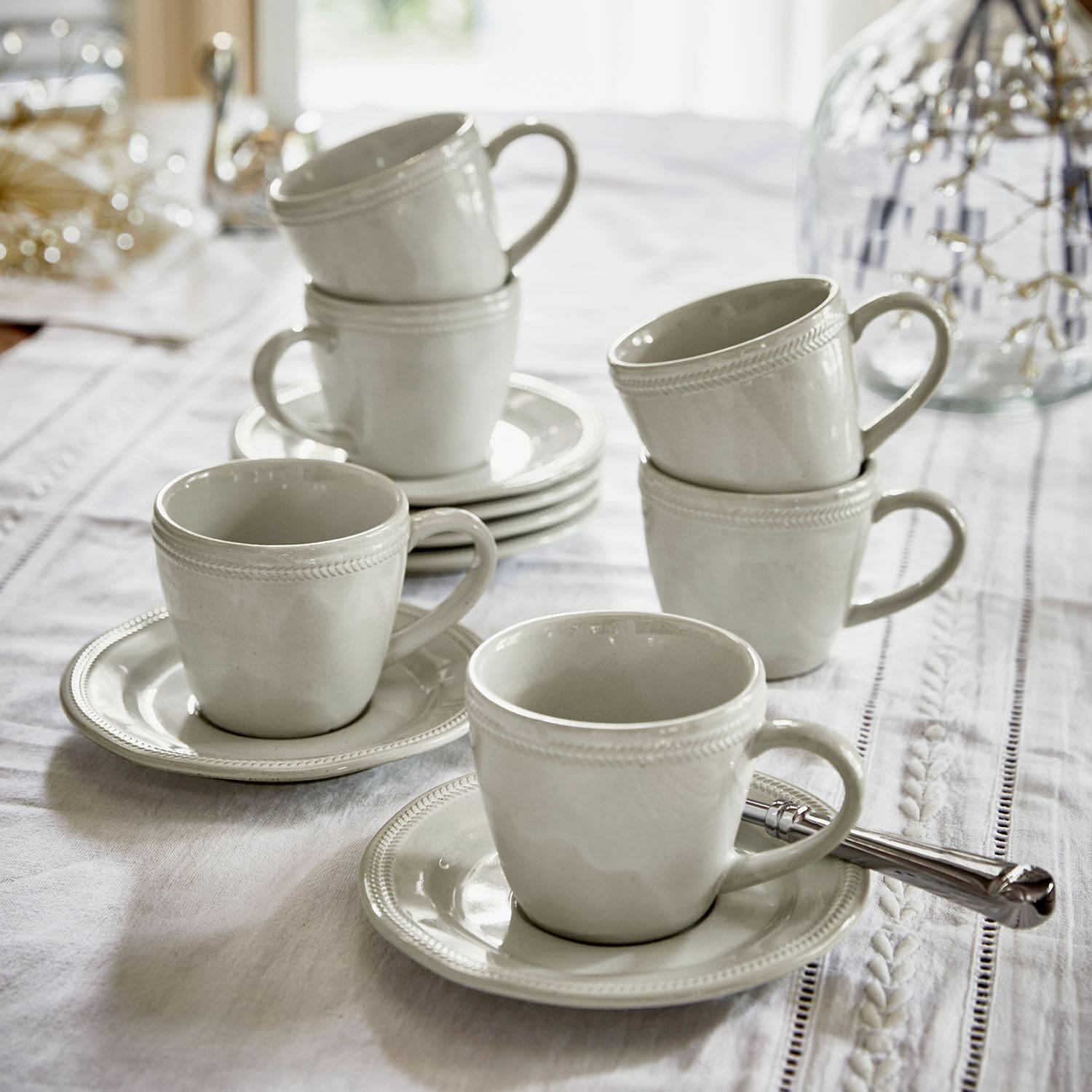 Set de 6 tazas con platillos Norrvik Juego de tazas de cerámica blanca con platos sobre mantel blanco para café y té
