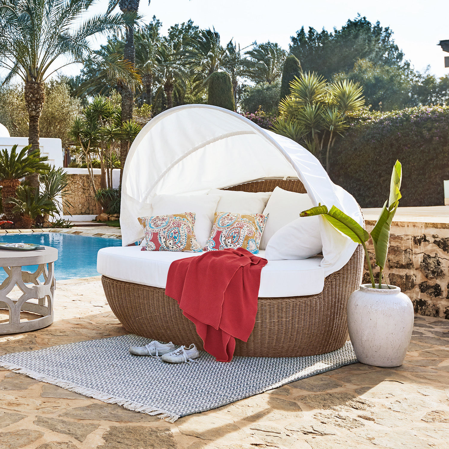Mueble de jardín redondo de ratán con cojín blanco y toldo, ideal para relajarse al aire libre