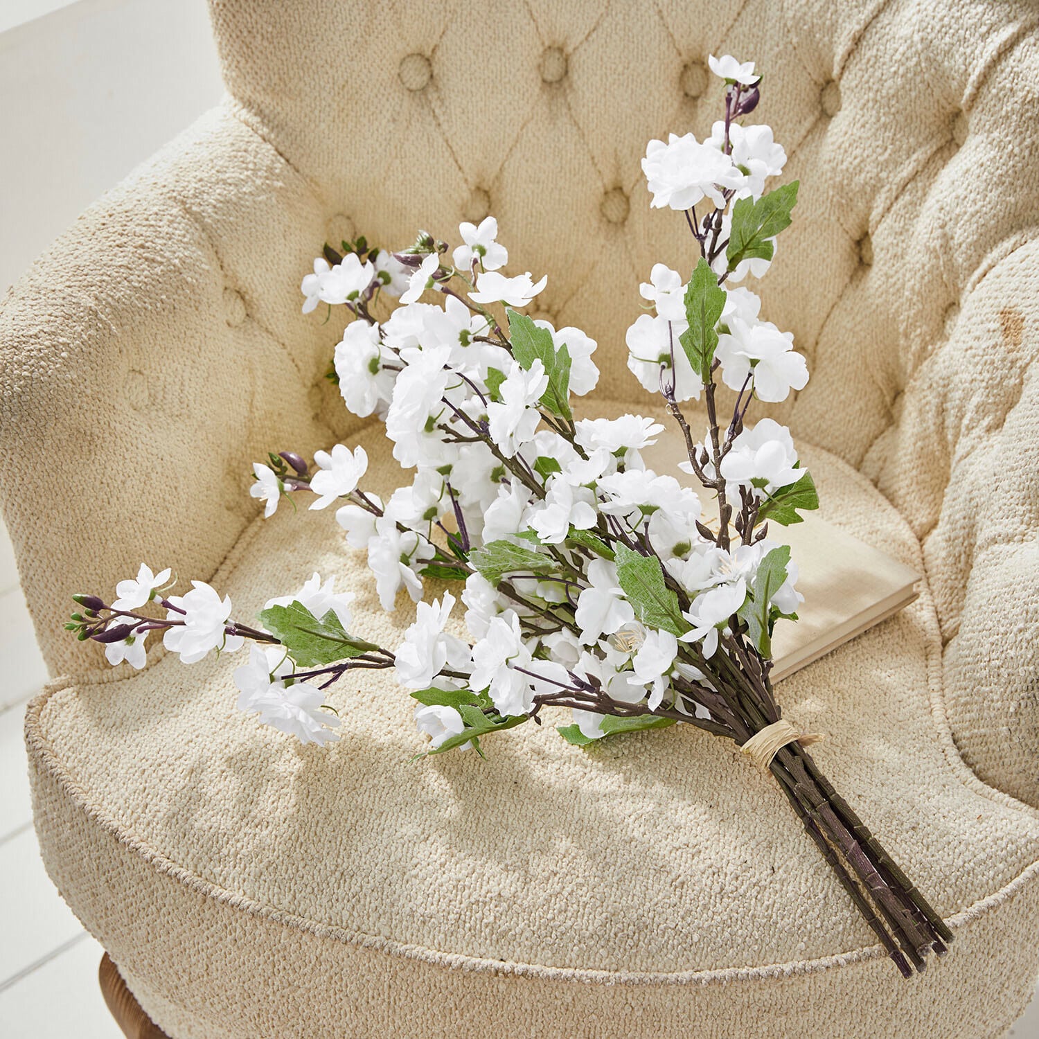 Set de 6 flores decorativas Bellévaut Ramo de flores blancas artificiales con hojas verdes sobre sillón beige texturizado