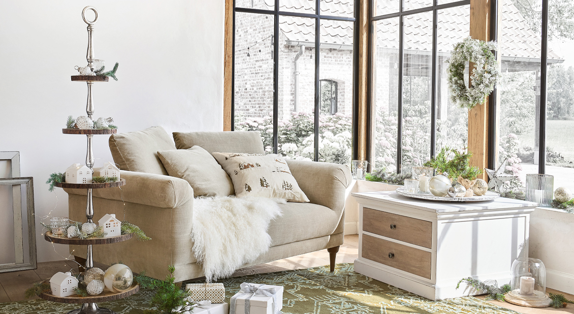 Acogedora sala de estilo rústico con sofá beige, cómoda blanca y decoración invernal festiva