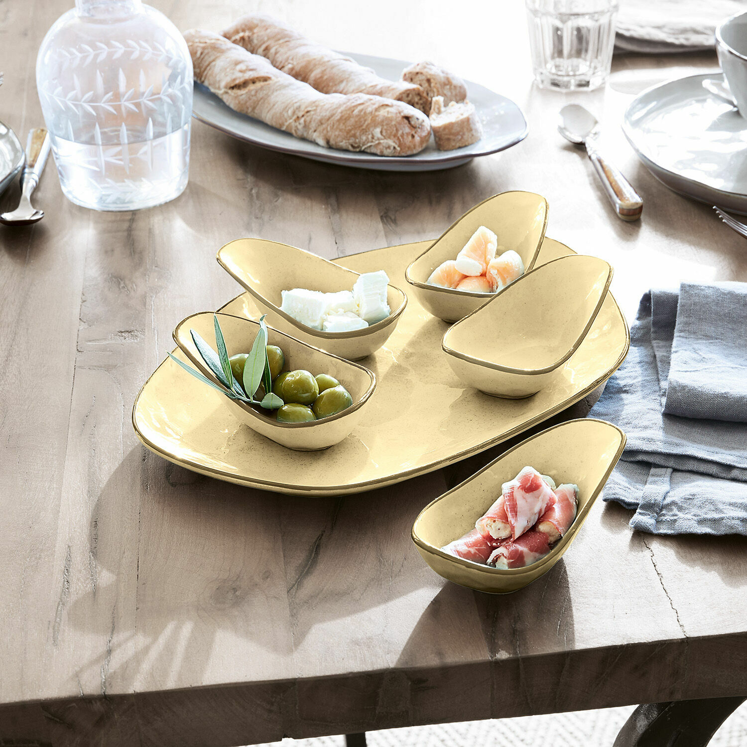 Set de 5 cuencos y plato de servir Biarré Juego de cuencos de cerámica amarilla para aperitivos sobre mesa de madera con aceitunas y queso
