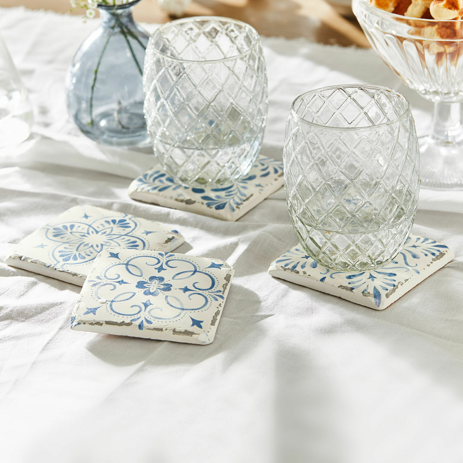 Posavasos de cerámica blanca con diseño azul sobre mantel claro para proteger superficies