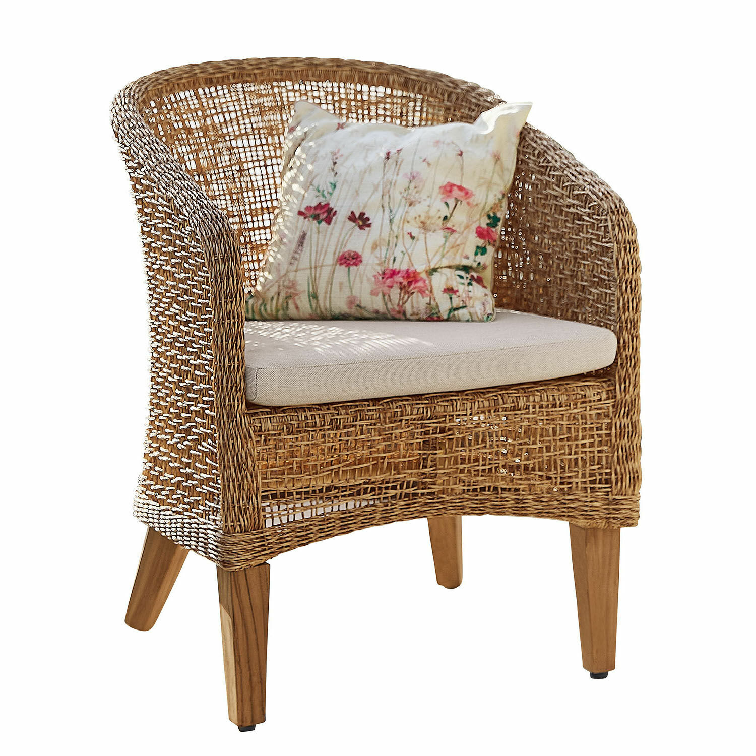 Sillón de ratán con cojín claro y funda floral, material natural y patas de madera