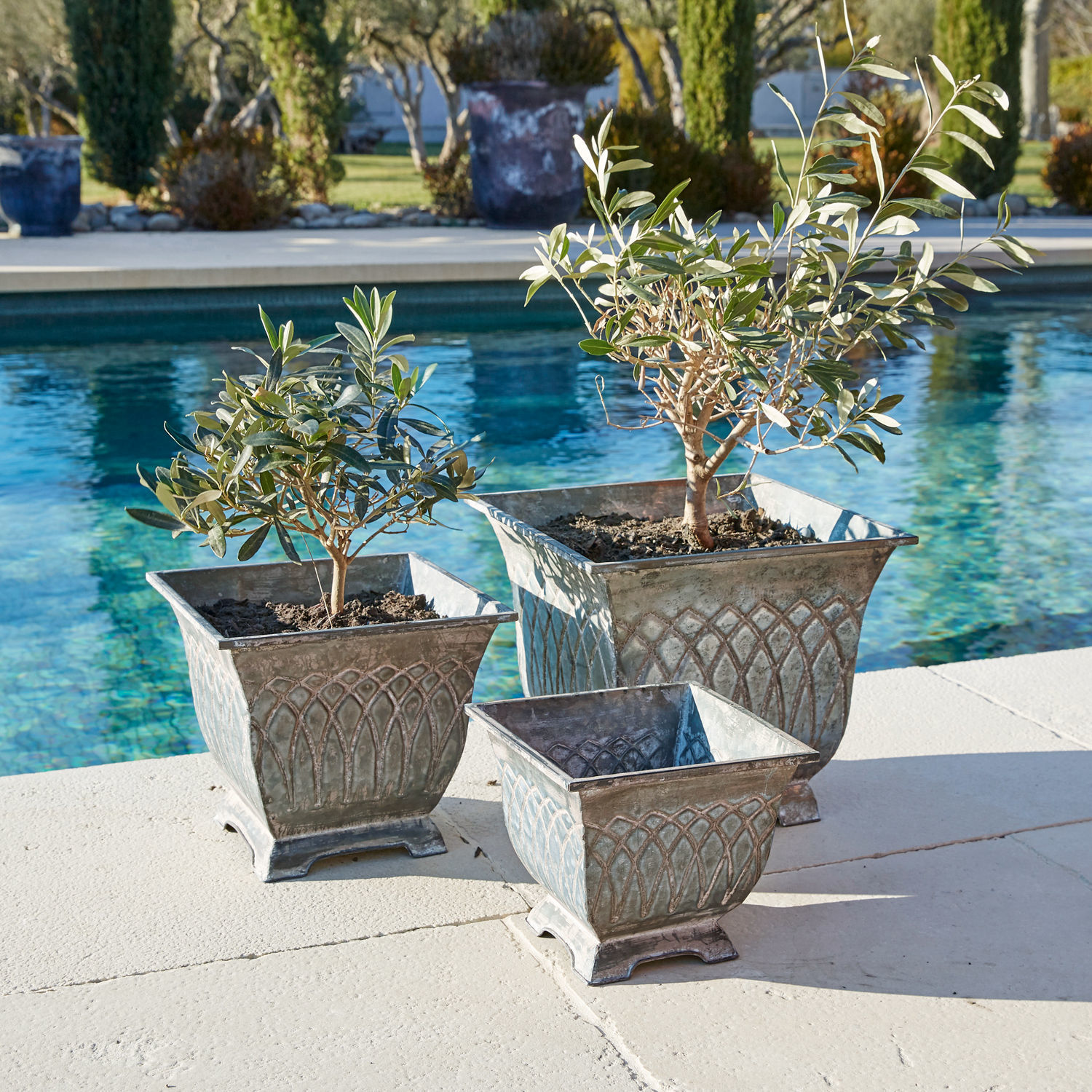Set de 3 macetas Klaireau Conjunto de tres macetas de metal gris estilo vintage junto a la piscina