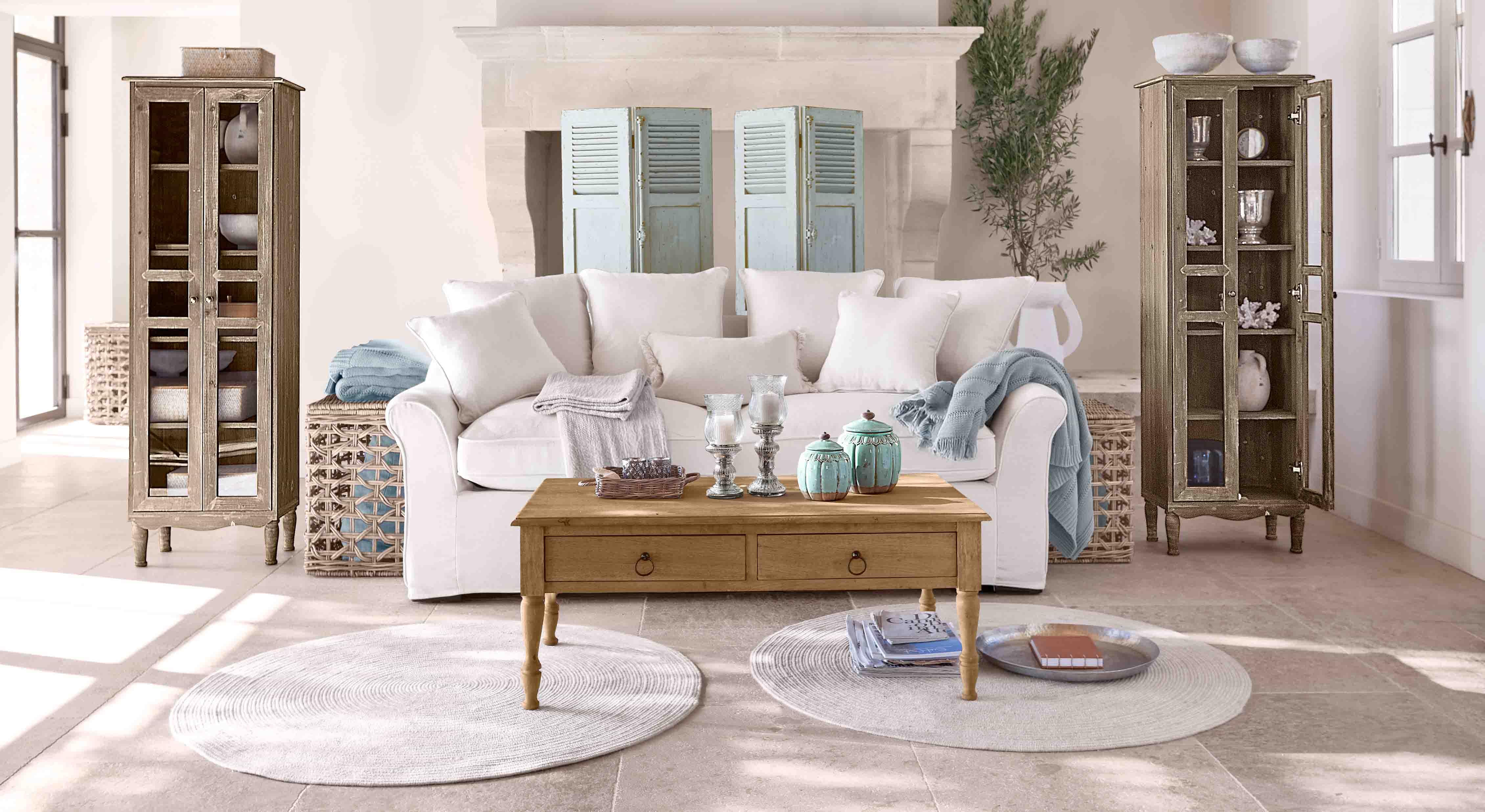 Sala acogedora con sofá blanco, mesa de madera y dos vitrinas de madera estilo vintage