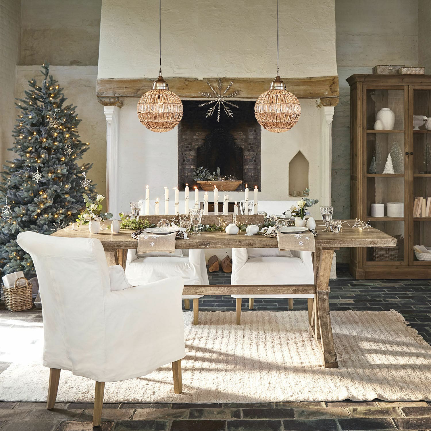 Mesa de comedor Dolignon Mesa rústica de madera con sillas blancas y decoración navideña en sala acogedora con chimenea