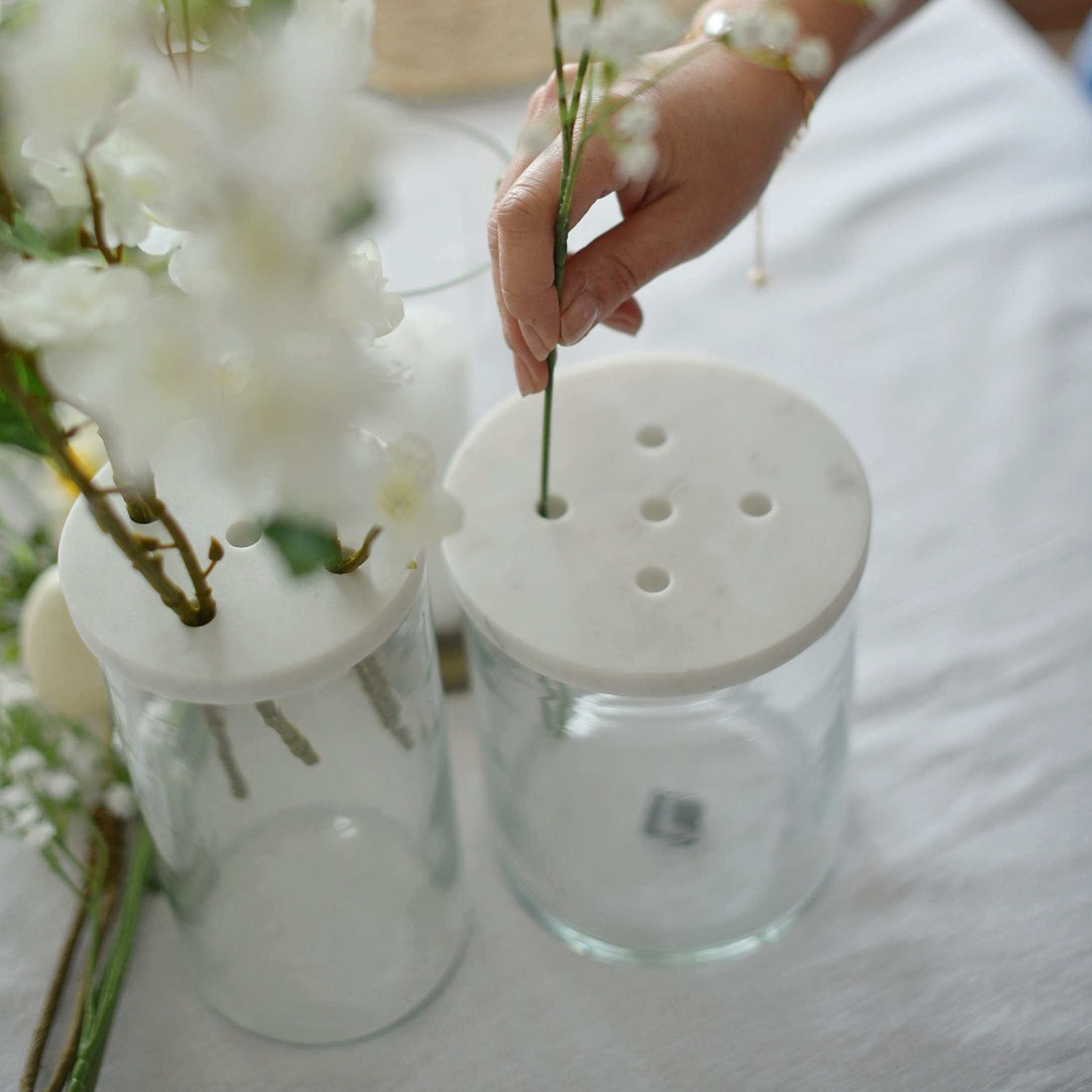 Jarrón de vidrio con tapa de mármol blanco perforada para arreglar flores sobre la mesa