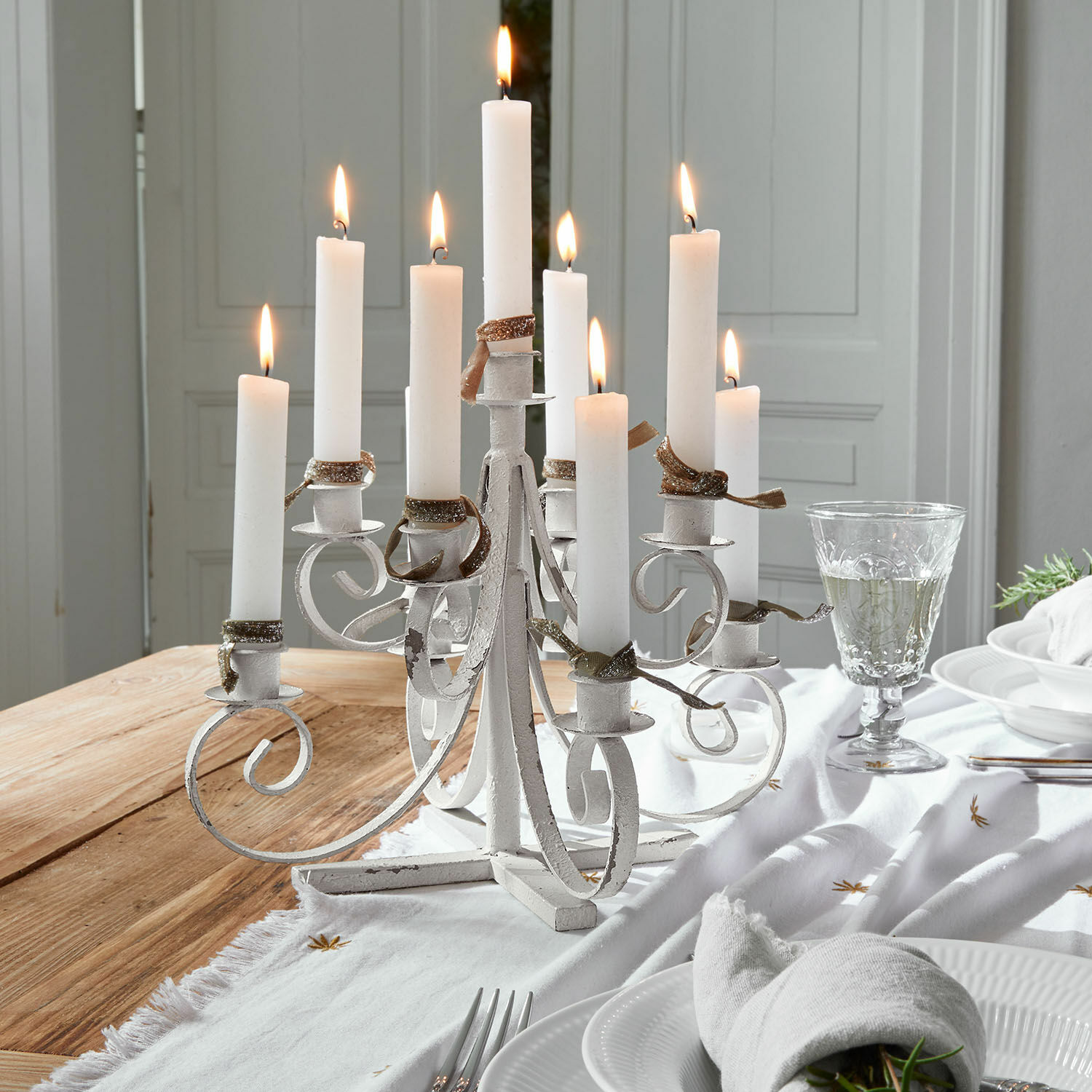 Candelabro Siolagh Candelabro blanco de metal con nueve velas encendidas sobre mesa de madera decorada para cena