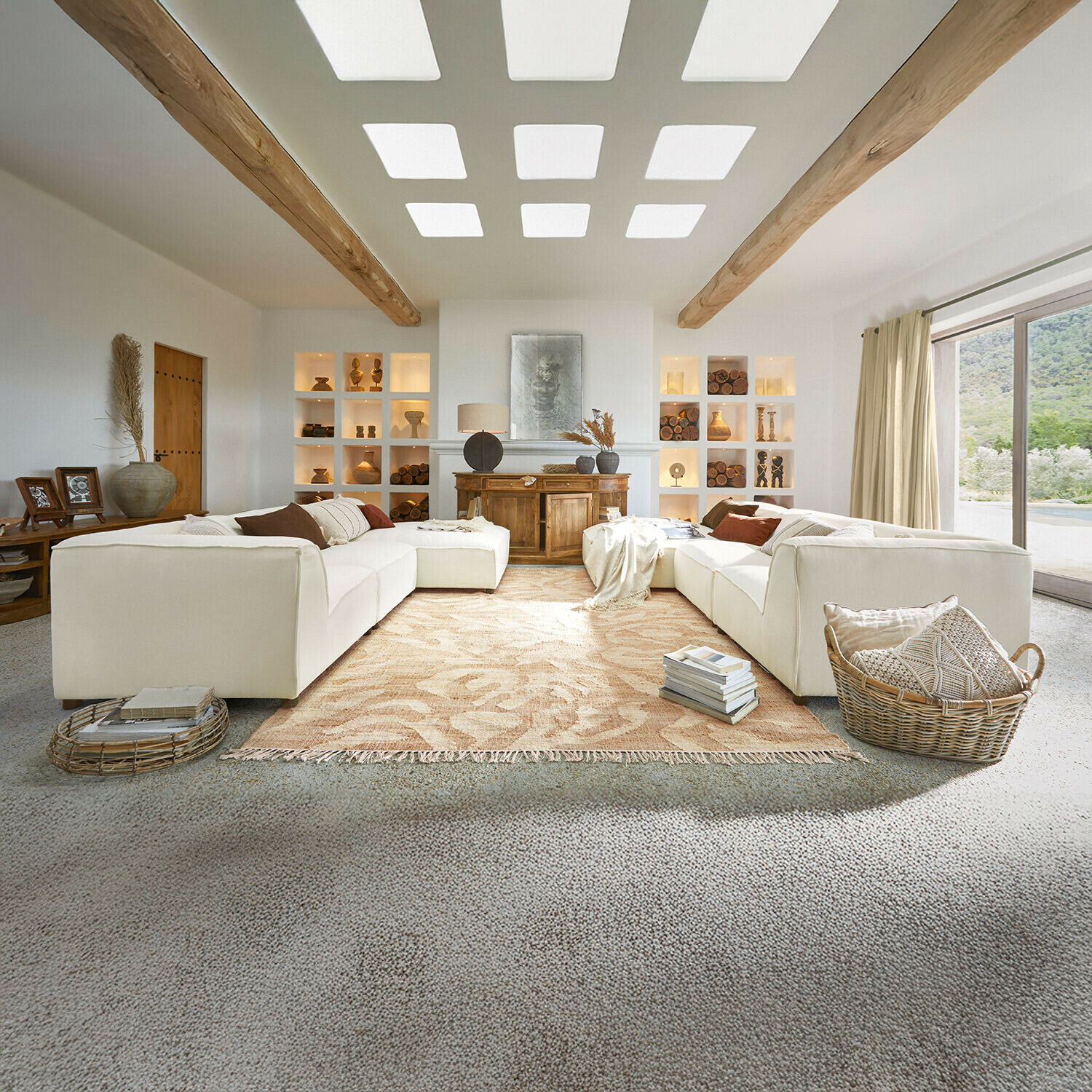 Sofá McLean Salón amplio con sofá blanco, vigas de madera, decoración natural, alfombra beige y ventana grande luminosa