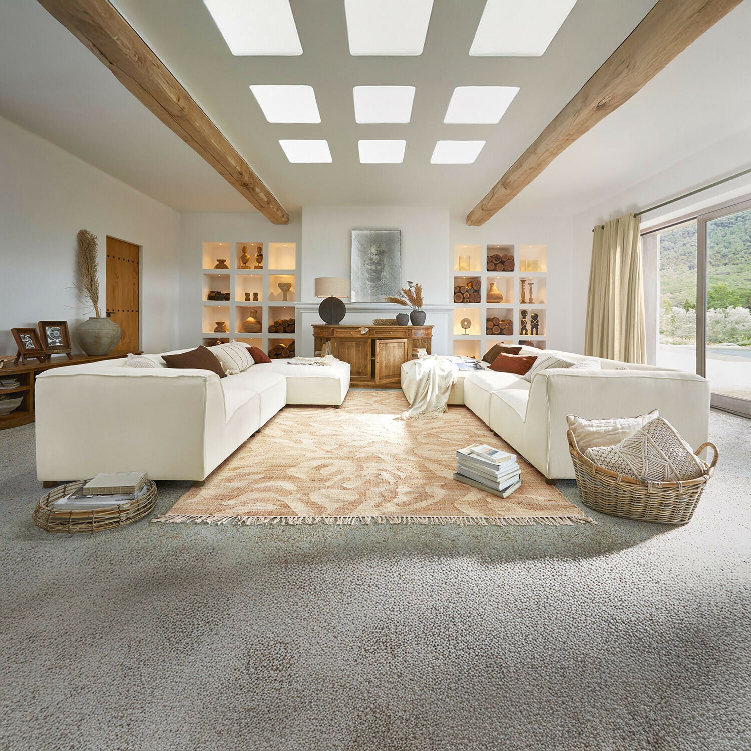 Sofá McLean Salón amplio con sofá blanco, vigas de madera, decoración natural, alfombra beige y ventana grande luminosa
