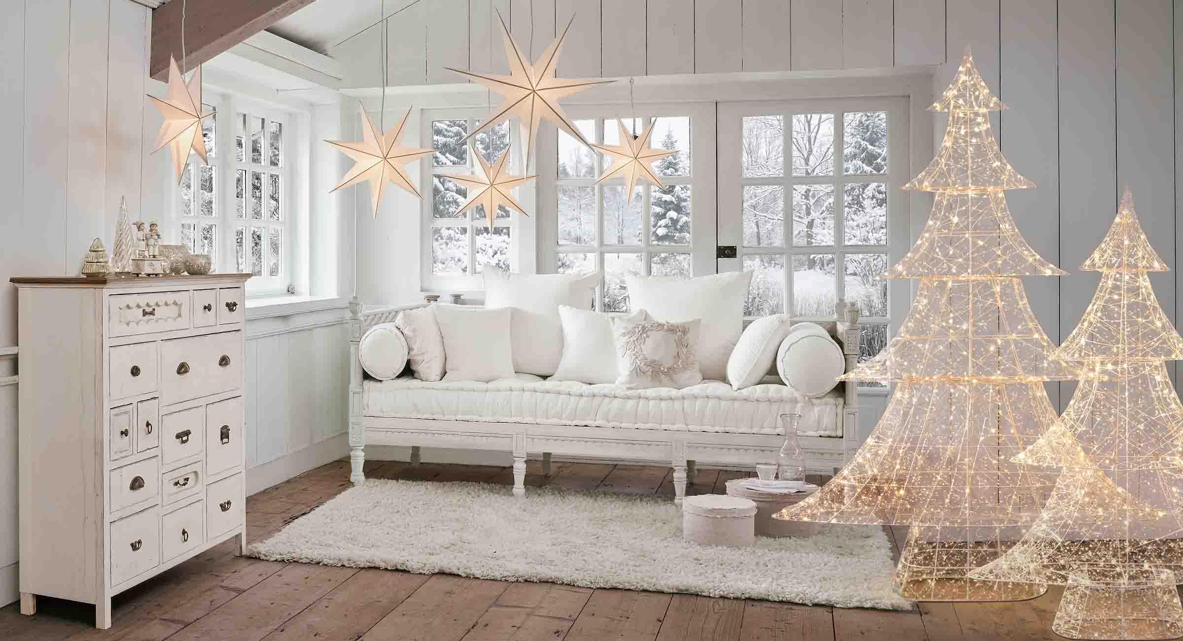 Acogedora sala blanca con decoraciones luminosas en forma de estrellas y árboles para invierno